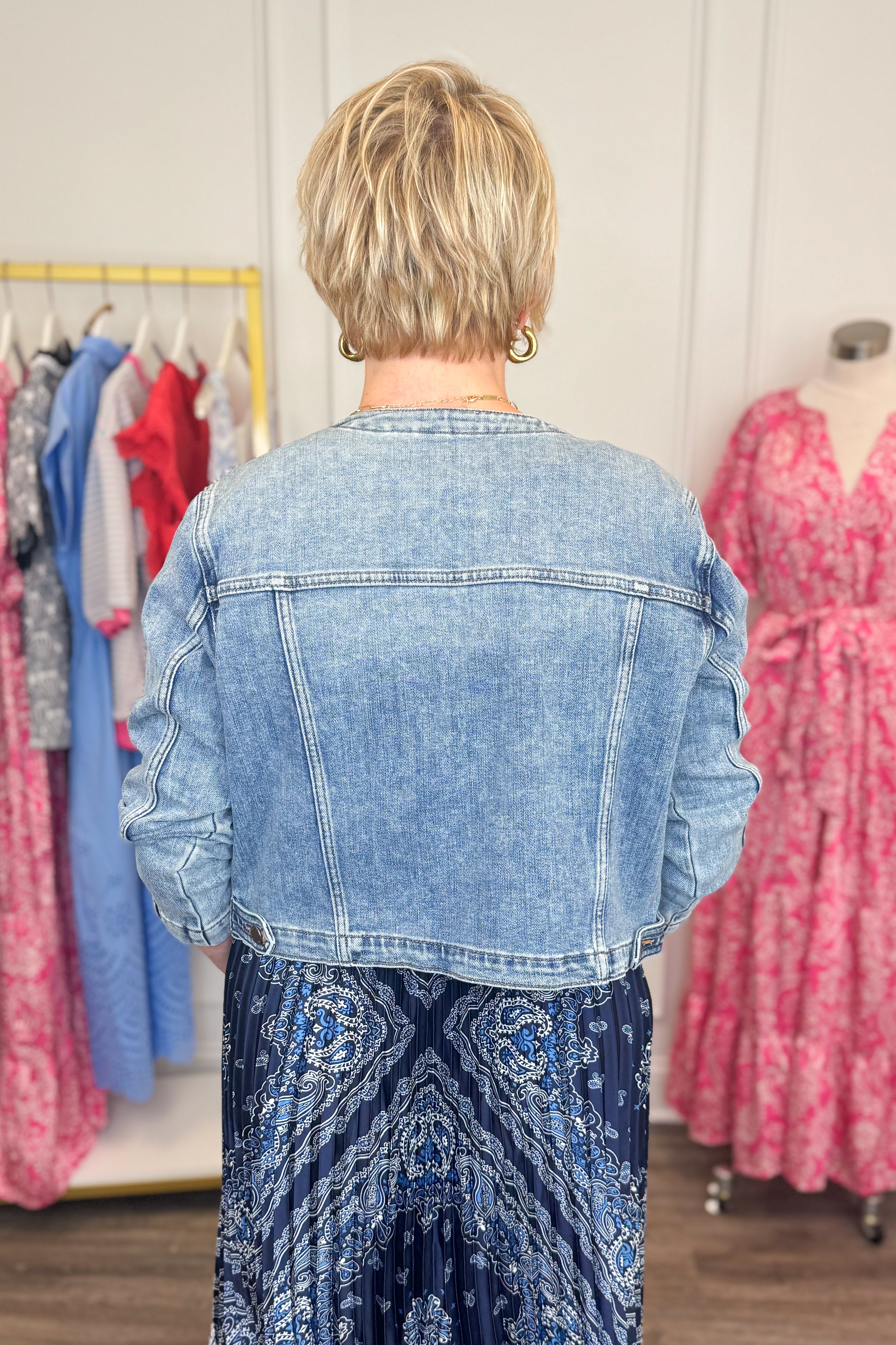 Back view of woman wearing Medium Wash Collarless Denim Jacket by Just Black Denim with top and skirt.