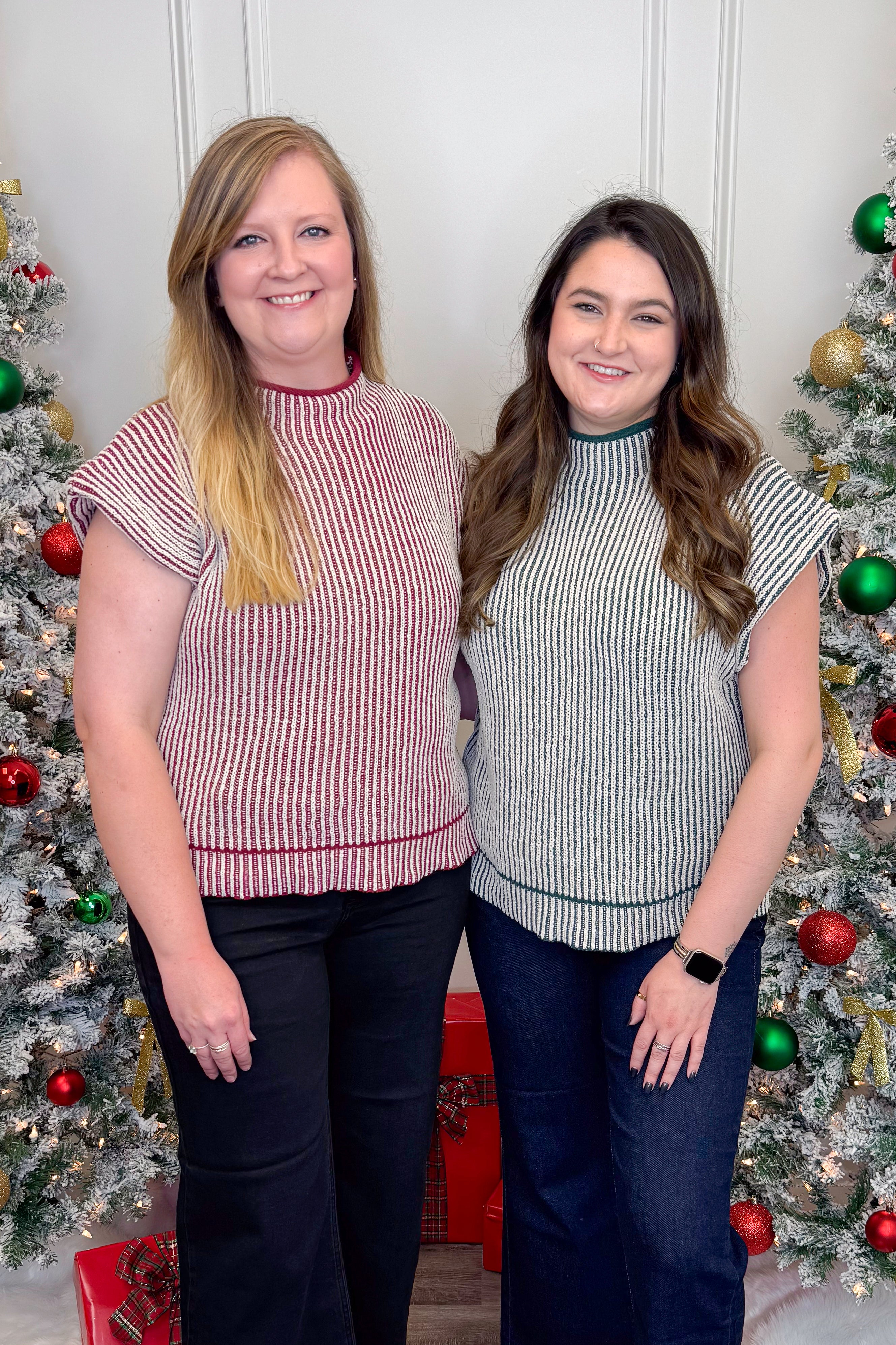 Two women standing in front of Christmas trees wearing matching outfits.