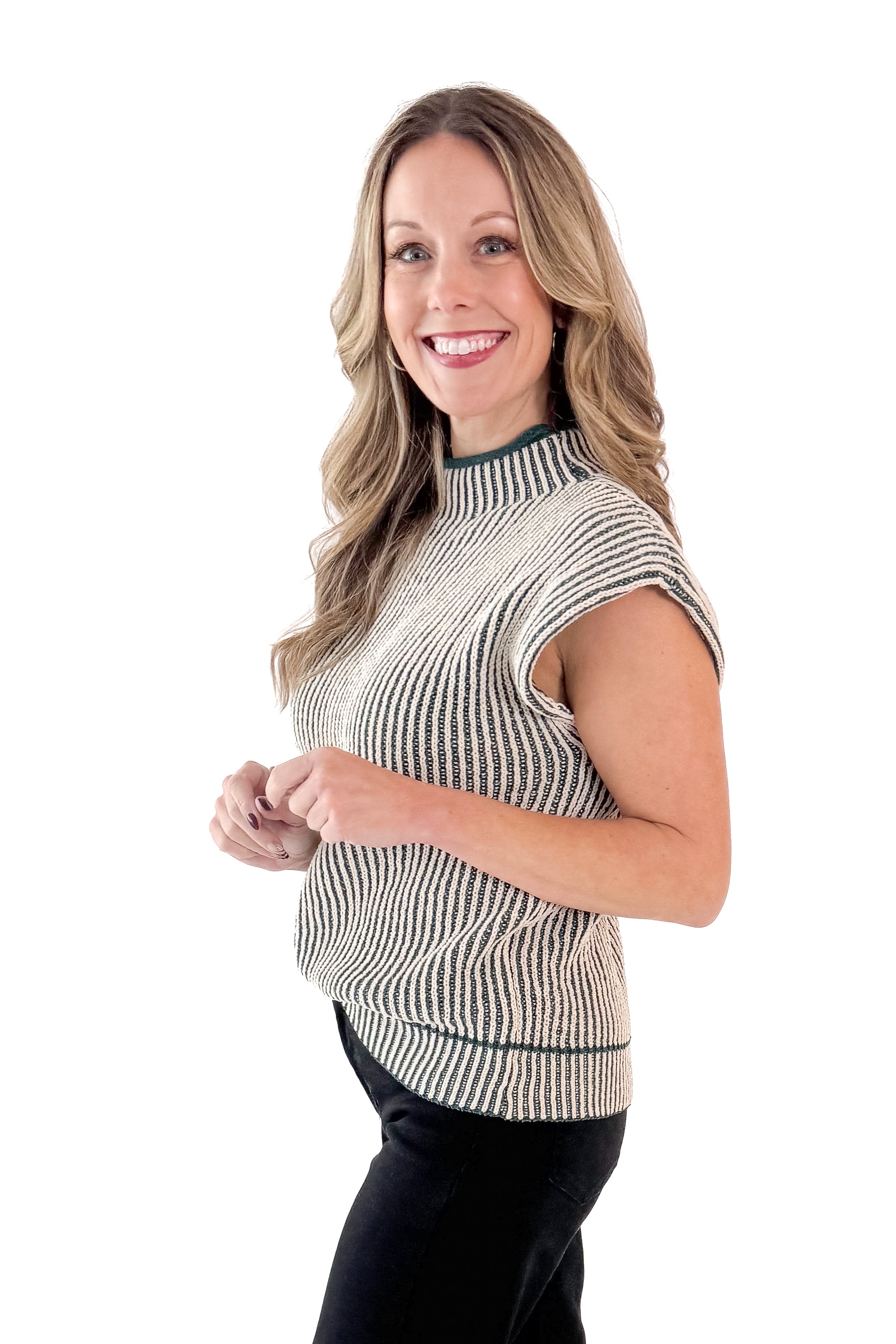 Side view of woman wearing sweater with jeans against white studio background.