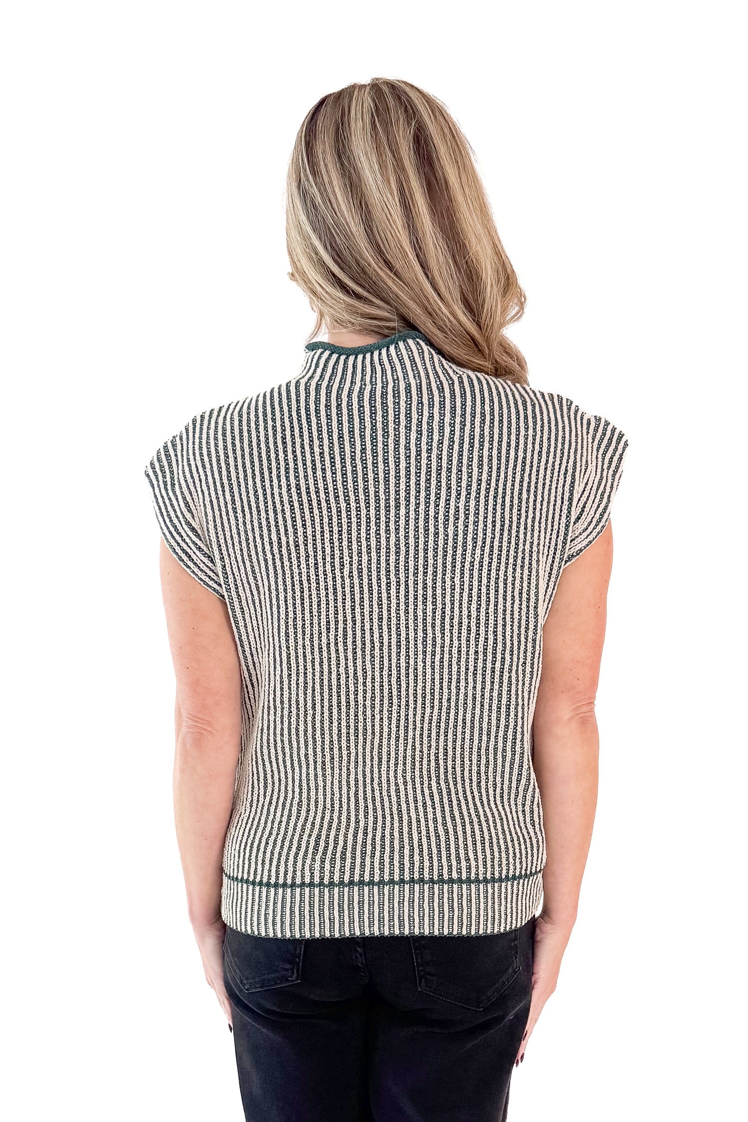 Back view of woman wearing sweater with jeans against white studio background.