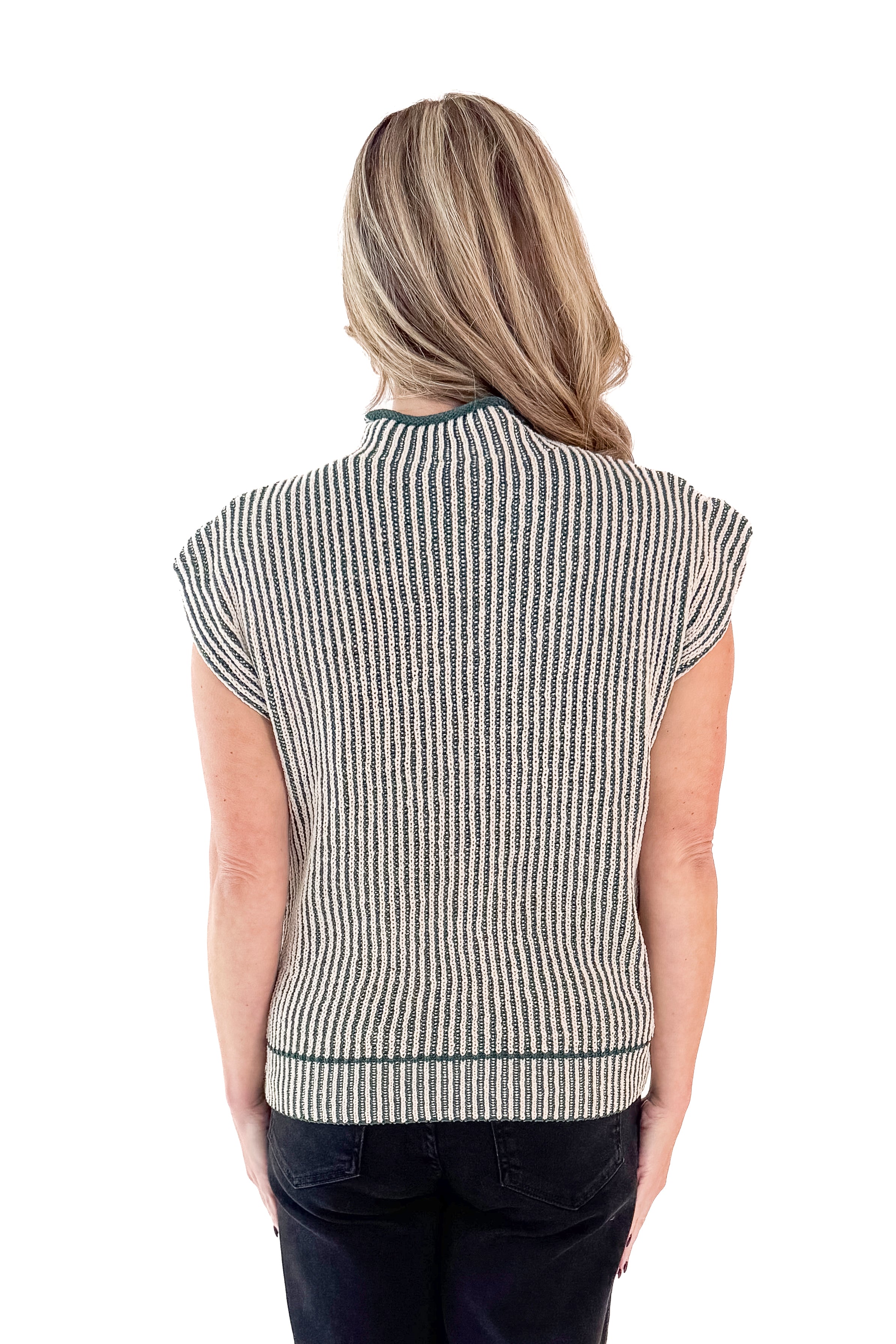 Back view of woman wearing sweater with jeans against white studio background.