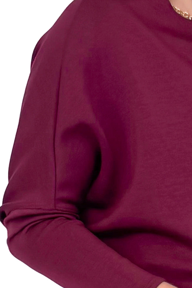 Front detailed view of woman wearing burgundy top against white studio background.