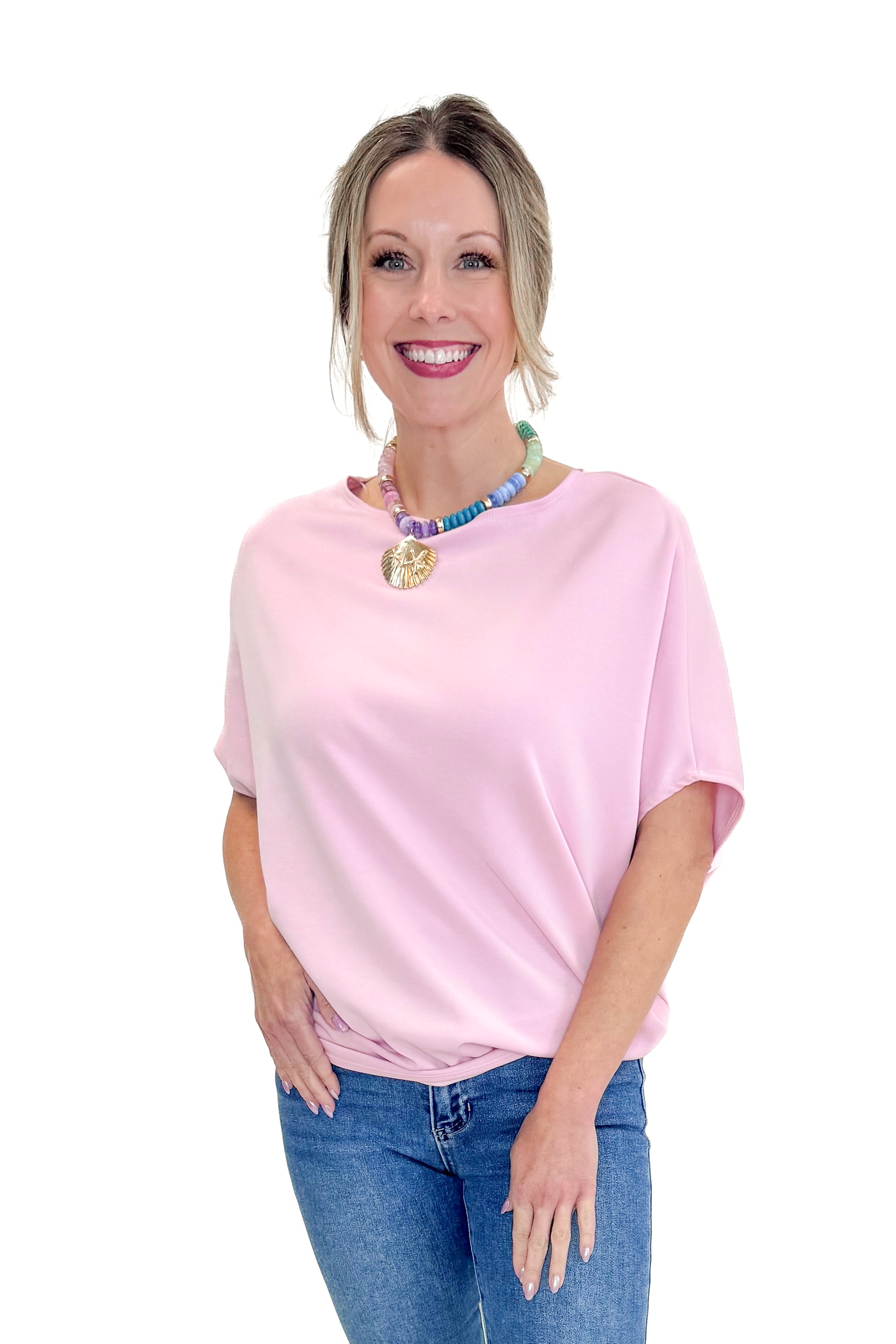 Front view of woman wearing Light Pink Dolman Sleeve Top with jeans against white studio background.