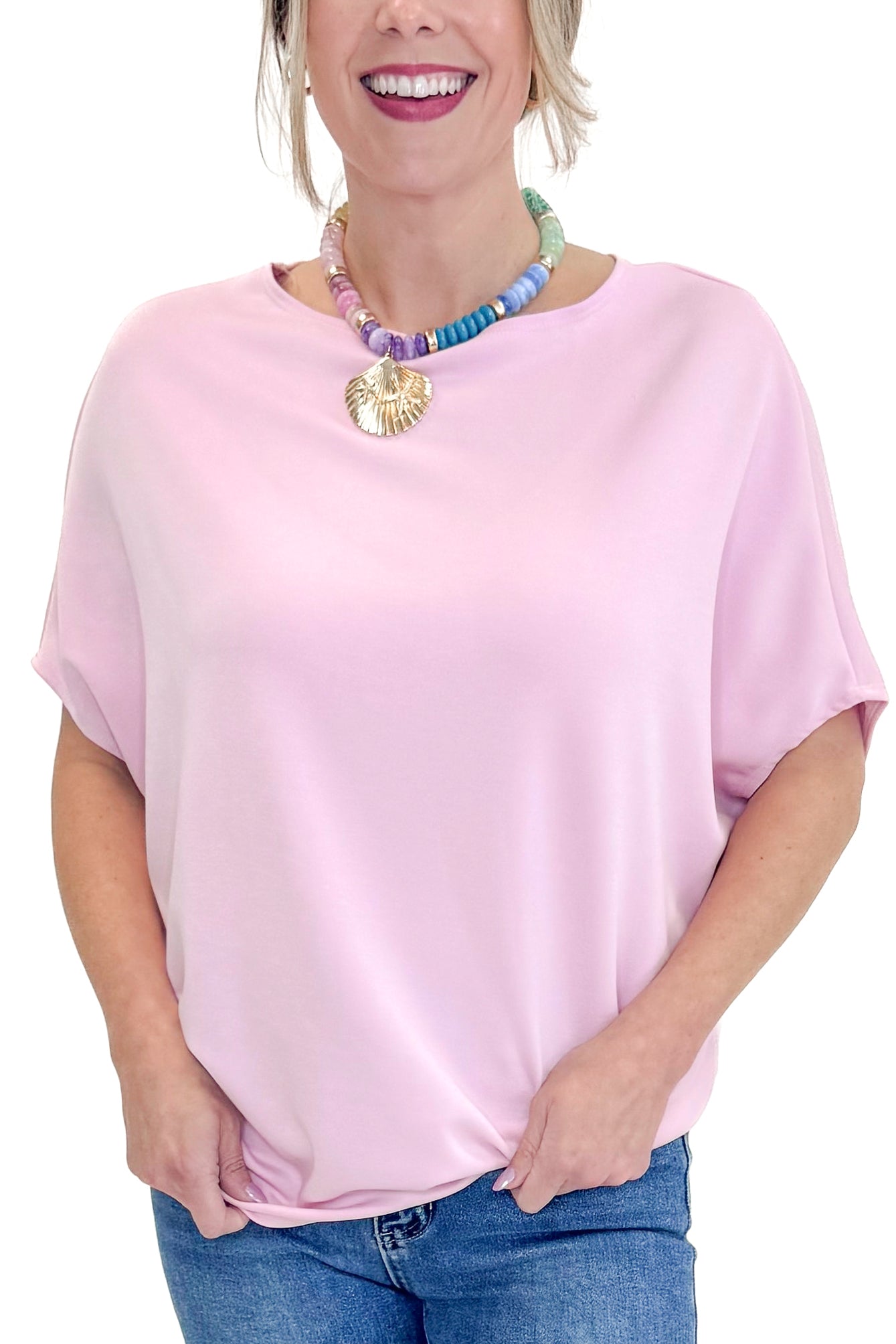 Front detail view of woman wearing Light Pink Dolman Sleeve Top with jeans against white studio background.