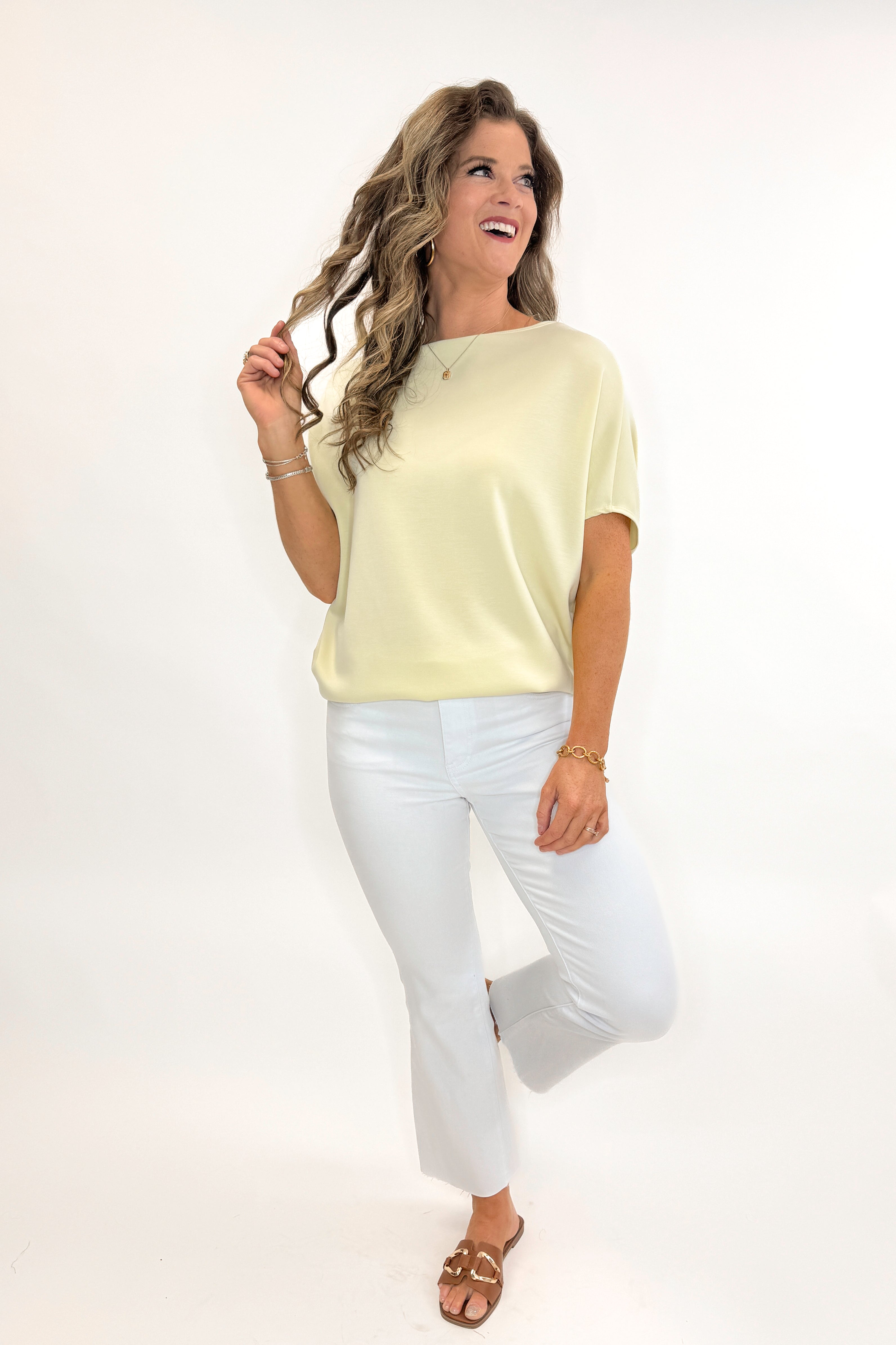 Front view of woman wearing Yellow Dolman Sleeve Top with white jeans against white studio background.