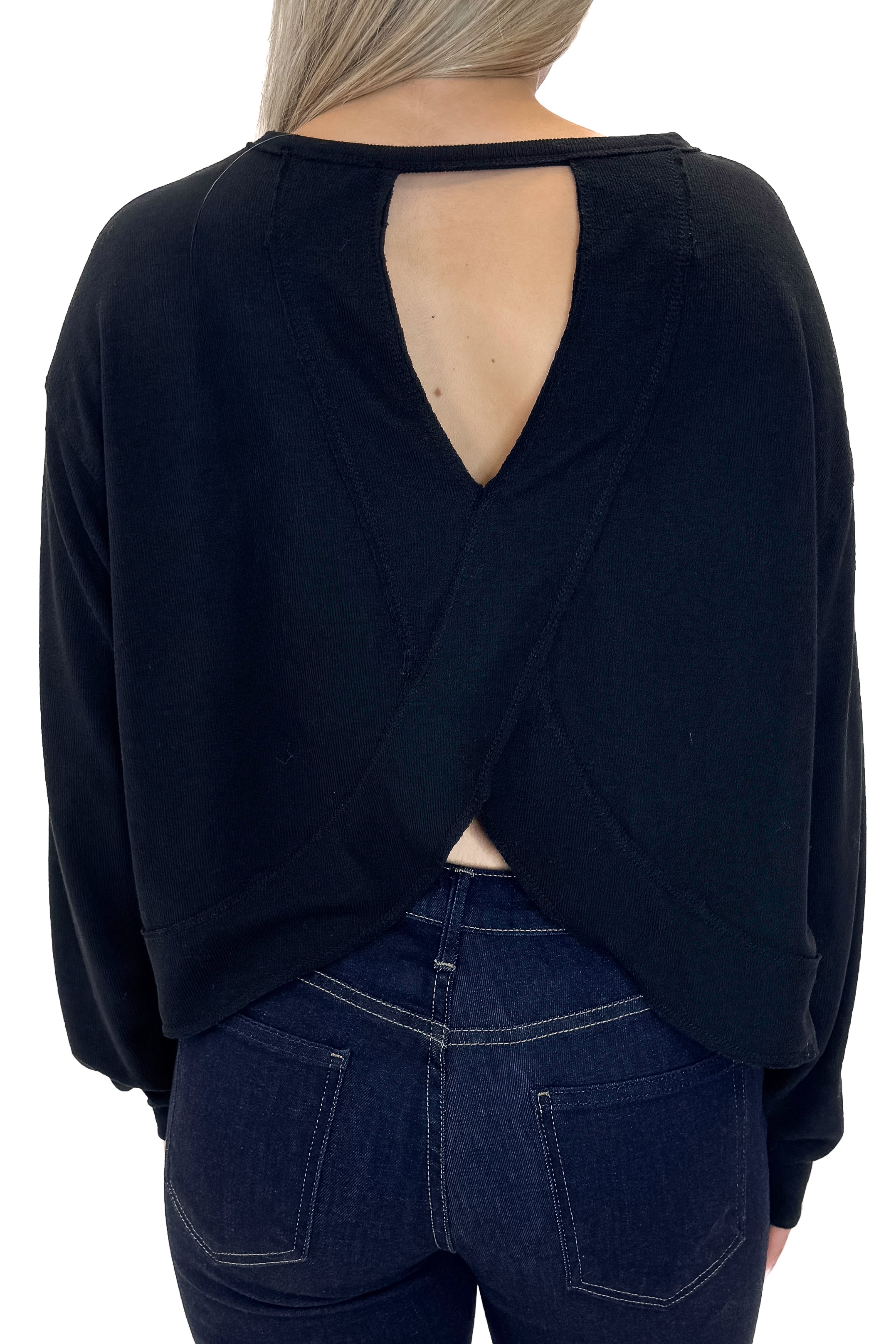 Back view of woman wearing Black Open Back Top with jeans against white studio background.