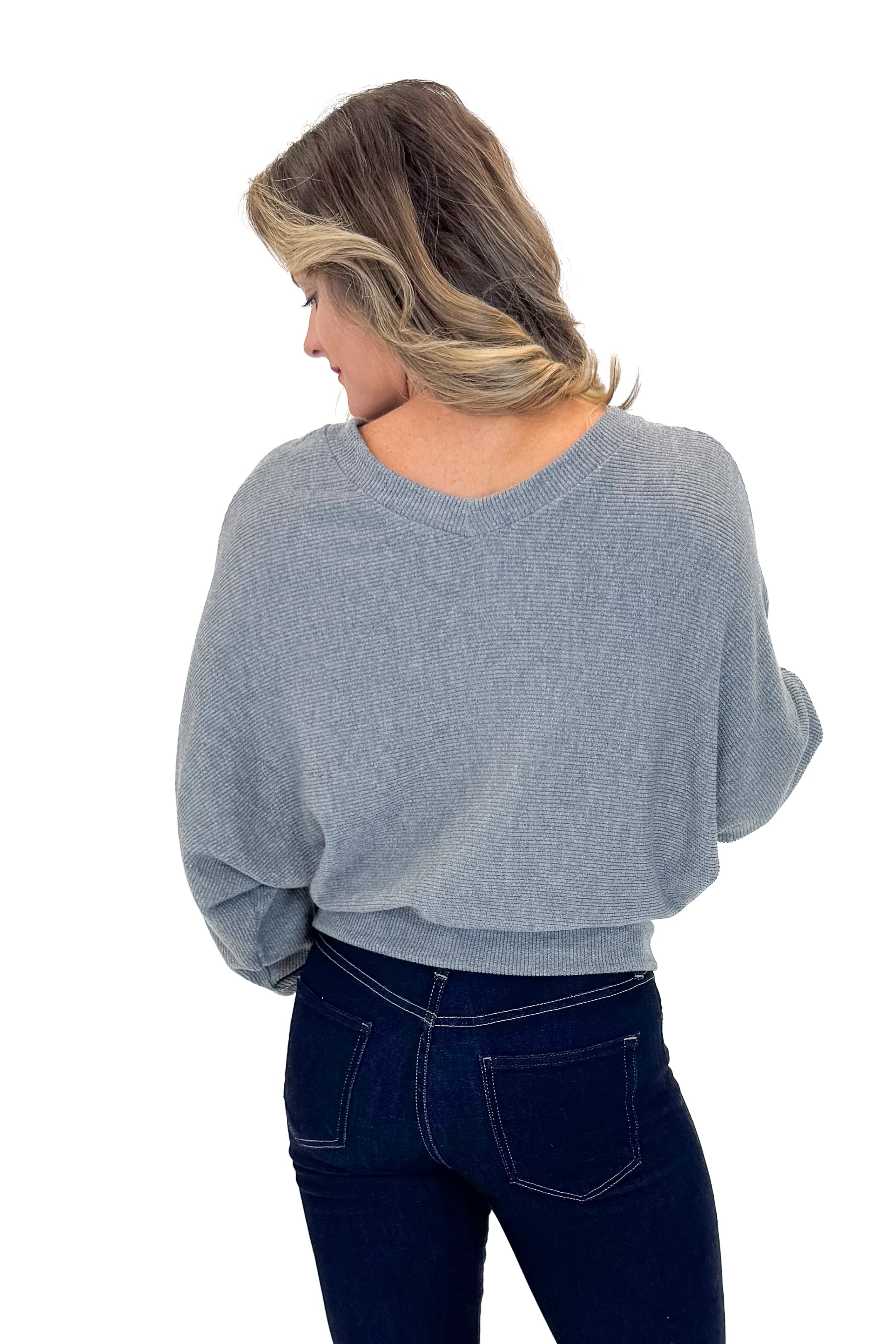 Back view of woman wearing Heather Grey Ribbed V-neck Banded Top with jeans against white studio background.