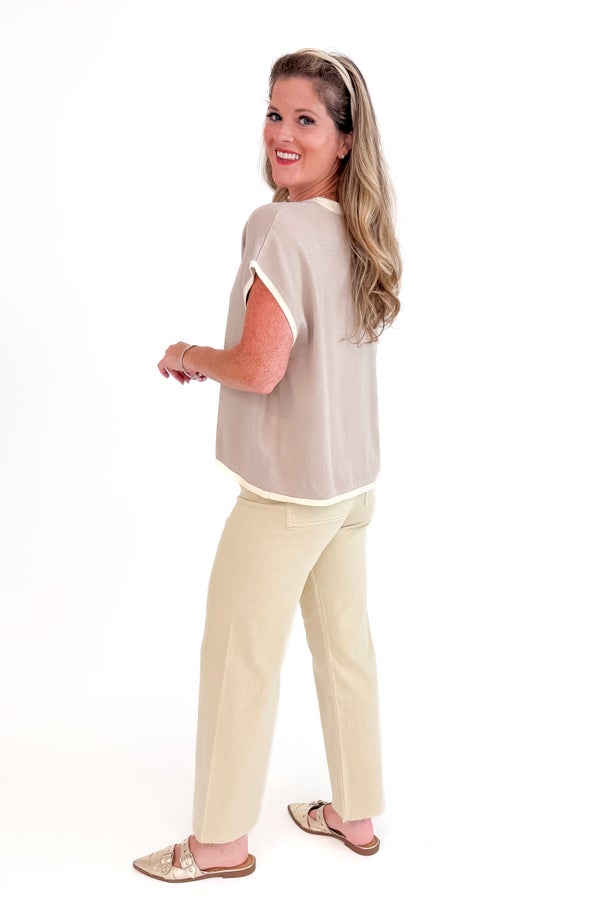 Woman wearing a beige top and pants on a white background