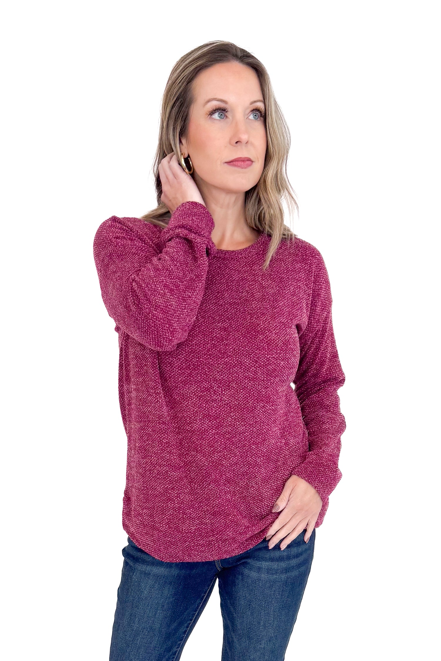 Woman wearing a maroon sweater and blue jeans on a white background