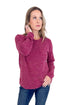Woman wearing a maroon sweater and blue jeans on a white background