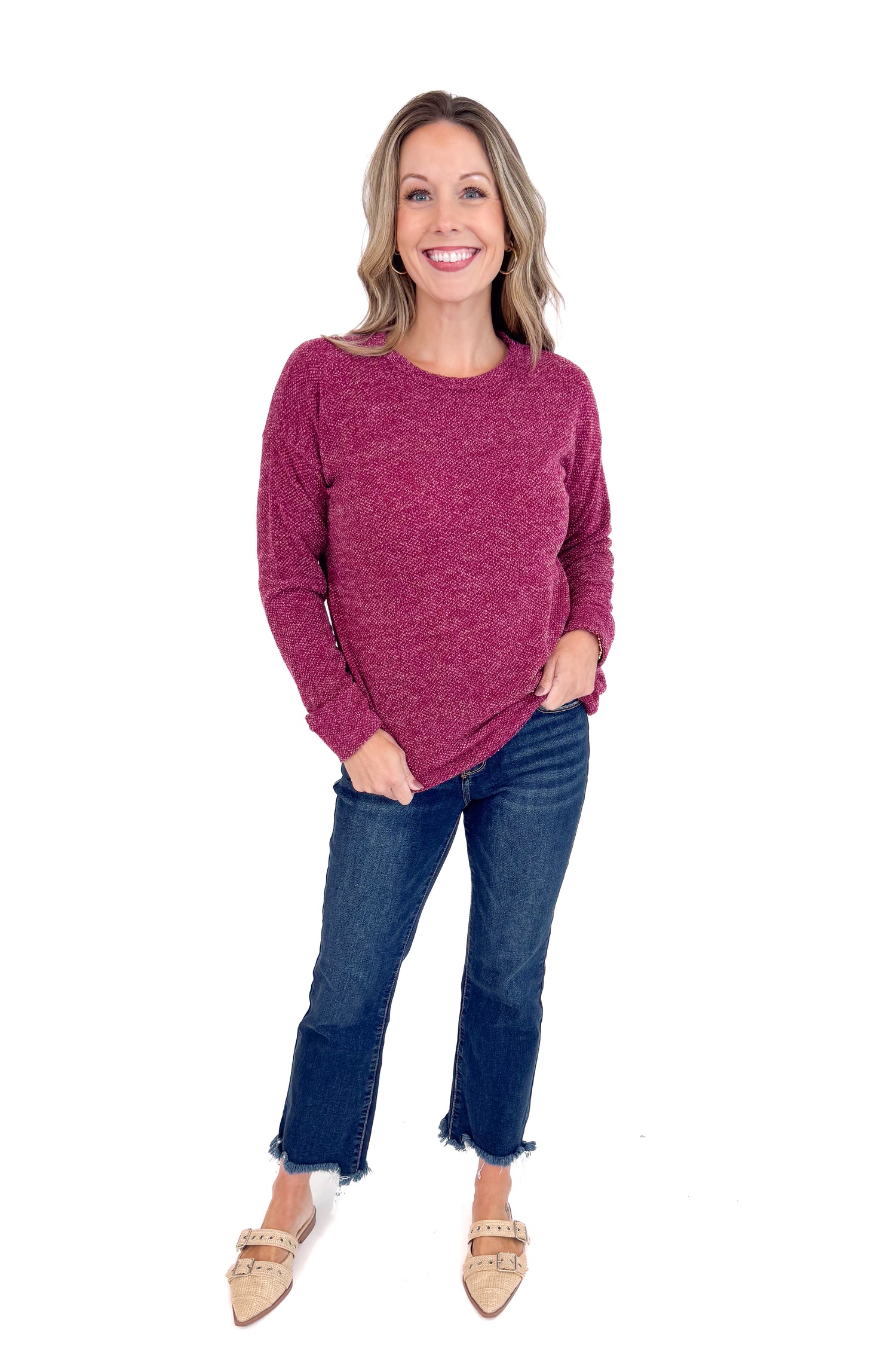 Woman wearing a maroon sweater and blue jeans on a white background