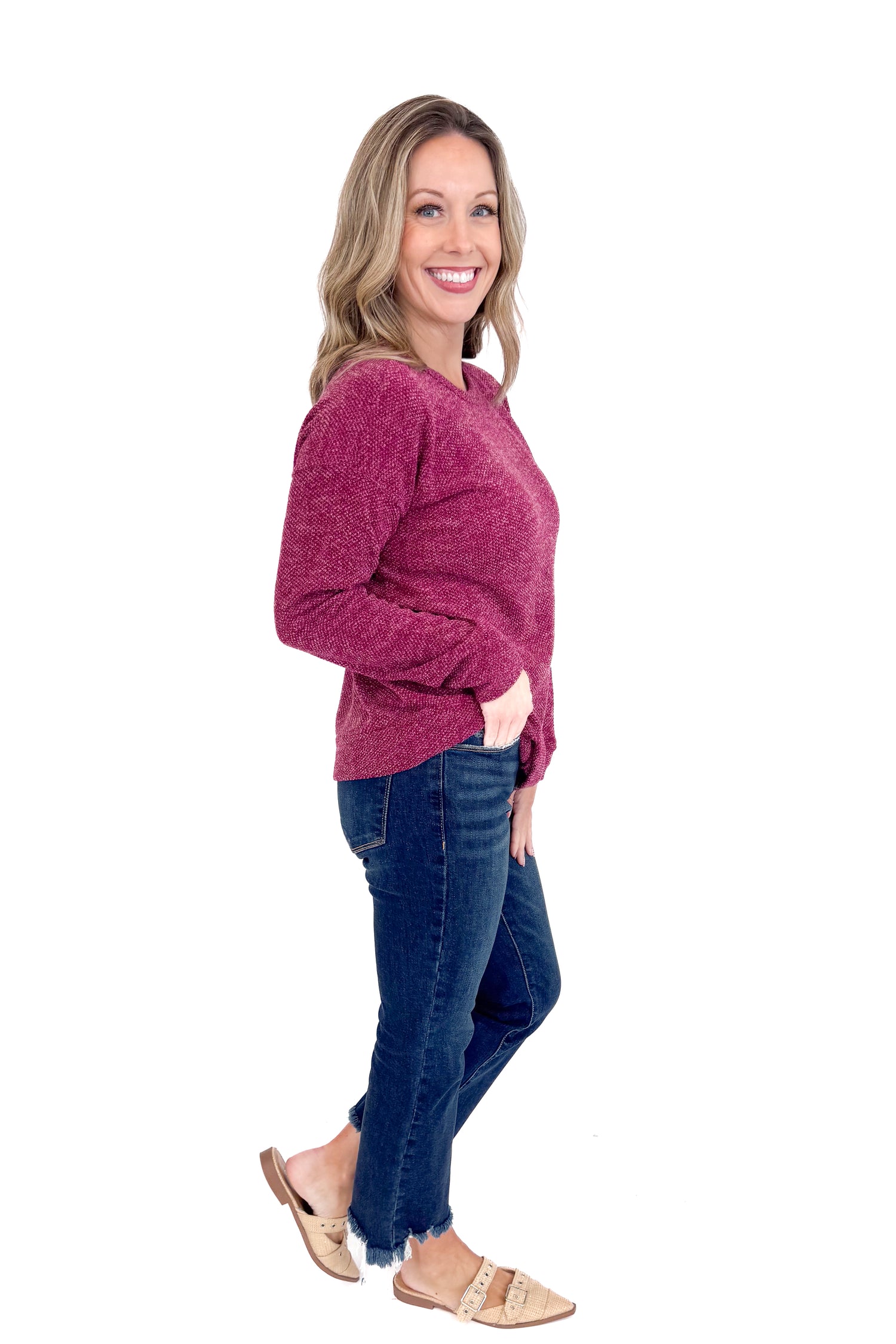 Woman wearing a maroon sweater and blue jeans on a white background
