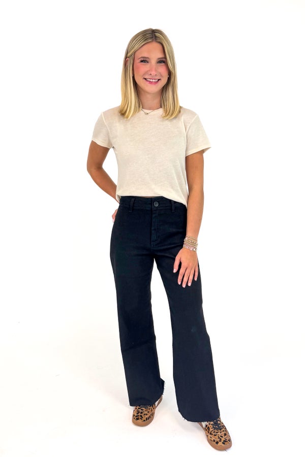 Woman wearing a beige t-shirt and black jeans on a white background