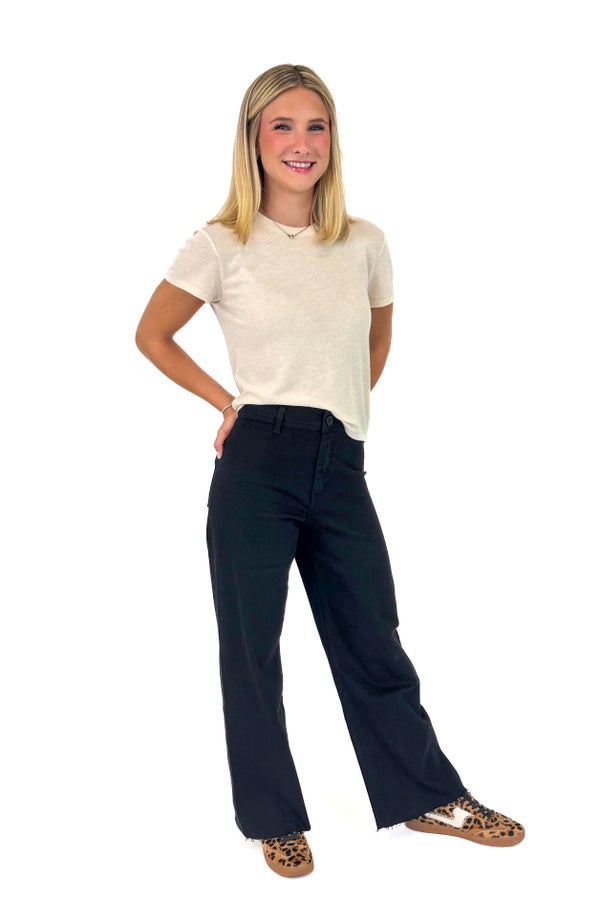 Woman wearing a beige t-shirt and black jeans on a white background