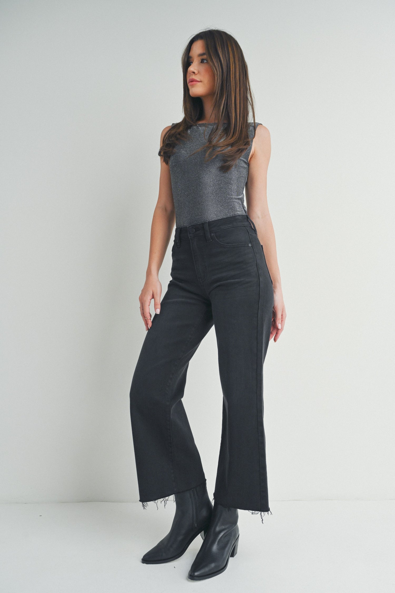 Stock photo of woman wearing washed black jeans and grey top against studio background.