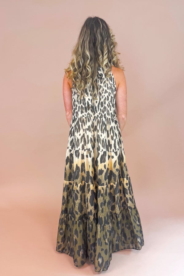 Woman in a leopard print dress standing in front of a beige background