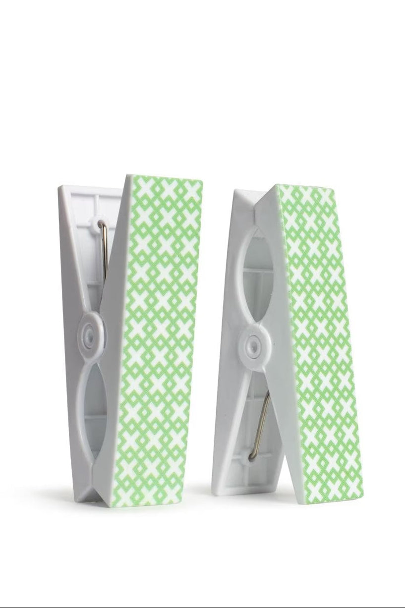 Two beach towel clips with green patterned straps on a white background