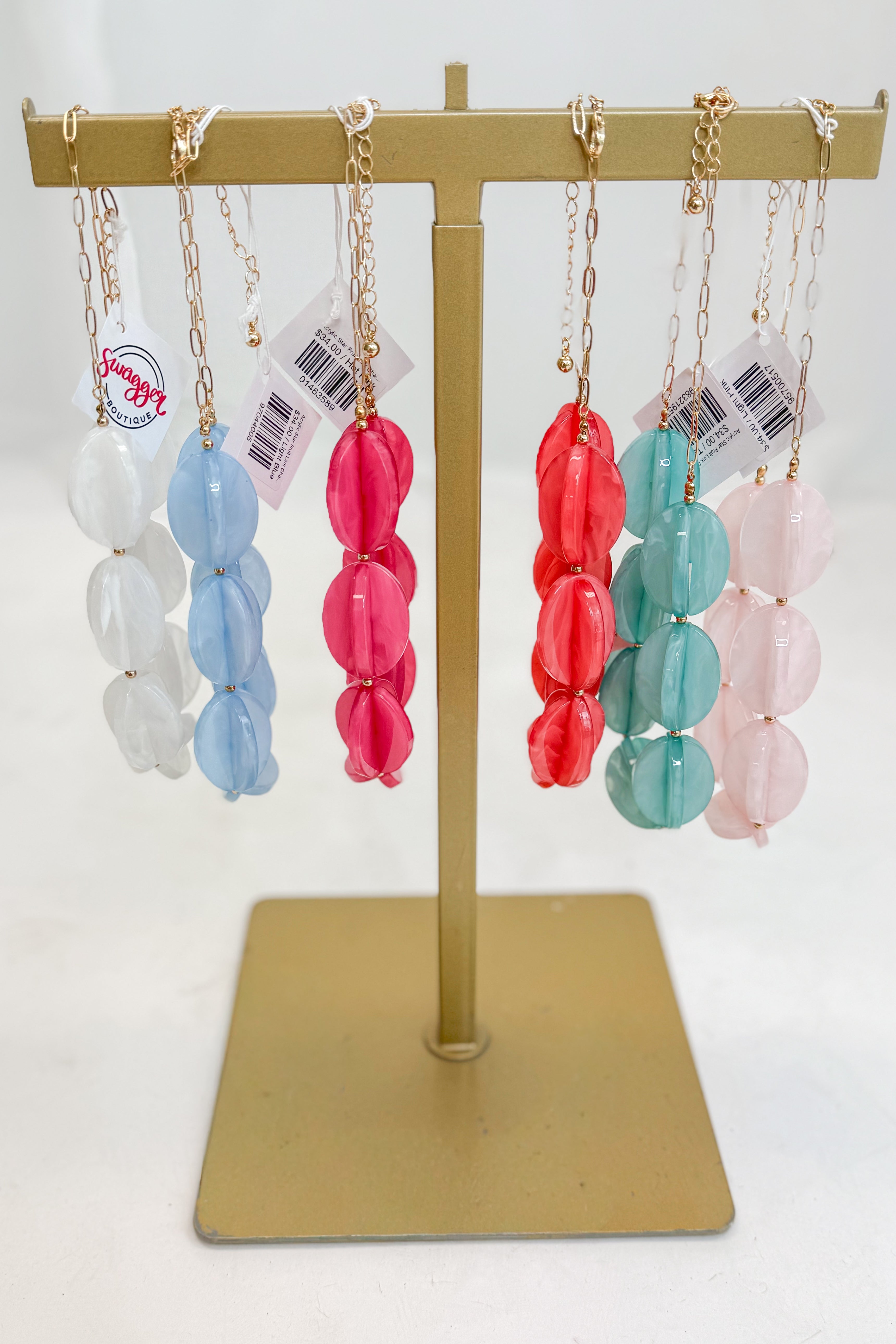 Colorful beaded necklaces on a gold display stand with a white background