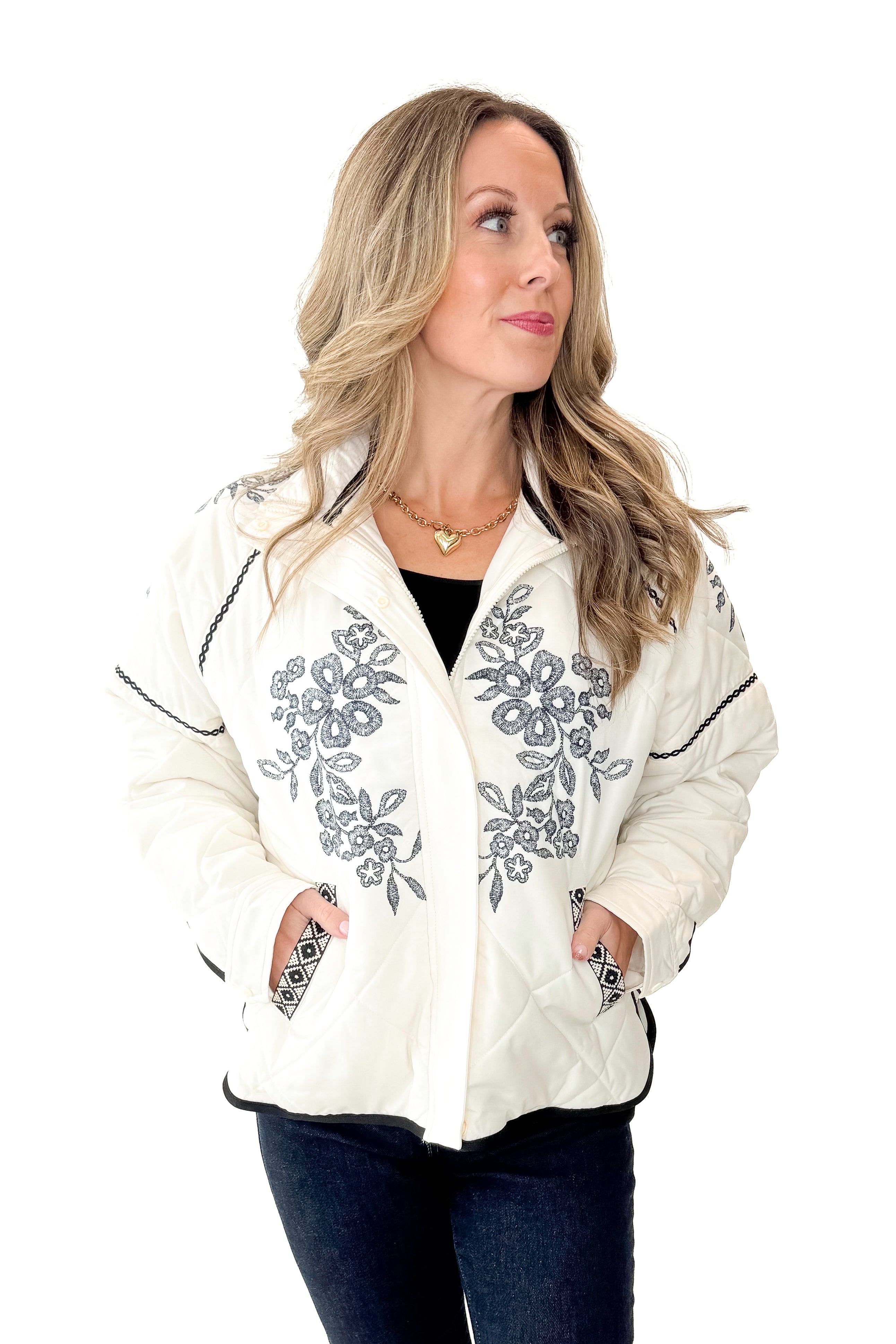 Front view of woman wearing Cream & Navy Embroidery Print Puffer Jacket with jeans against white studio background.