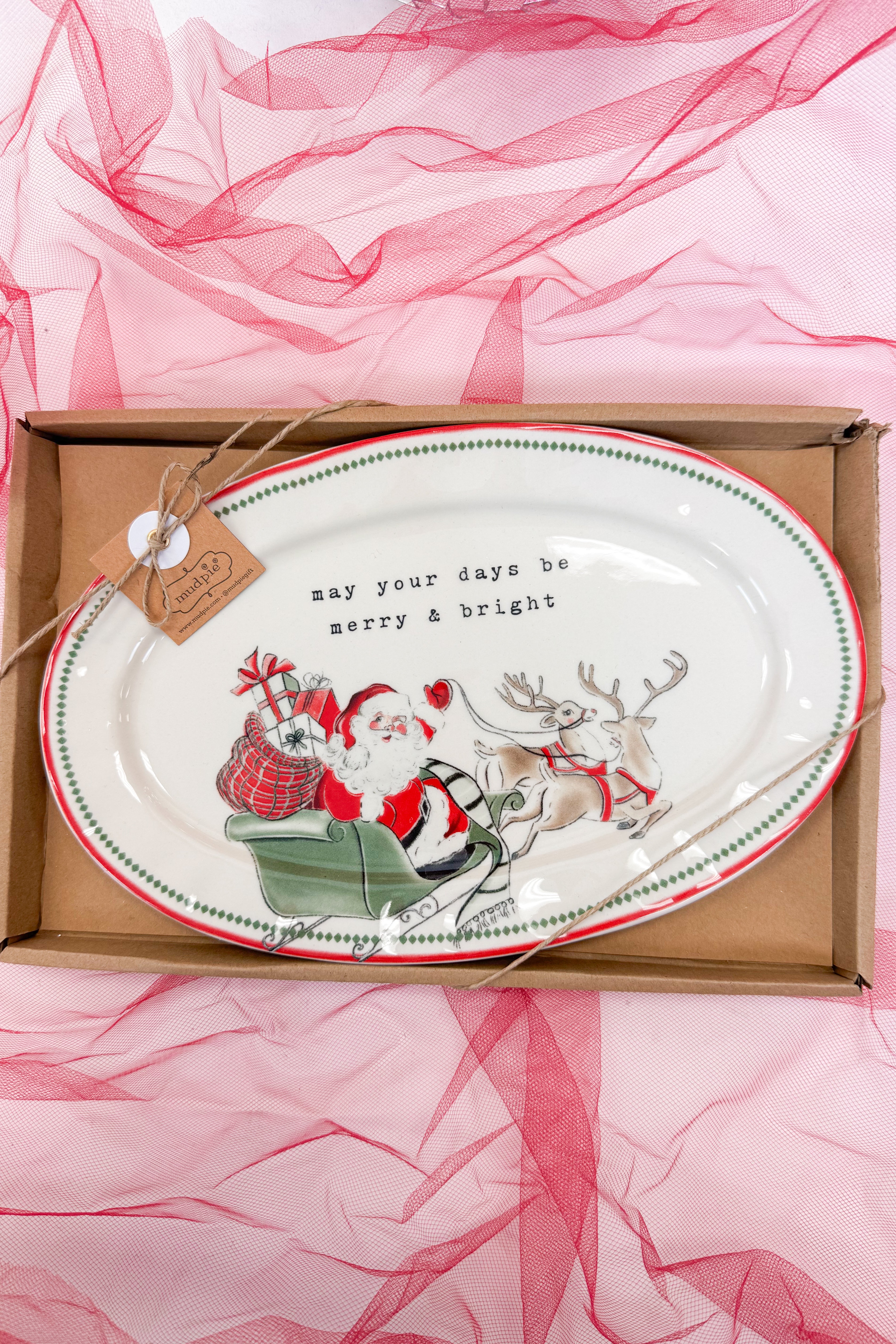 Decorative plate with Santa and reindeer design in a box on a pink fabric background