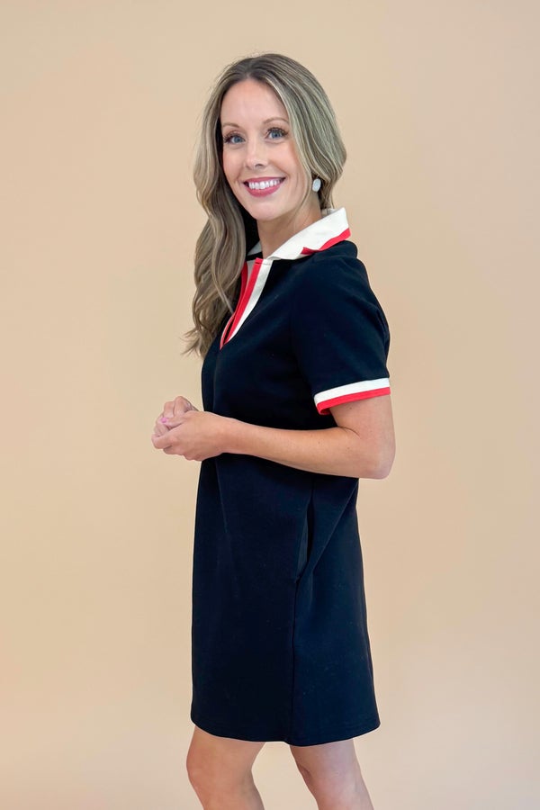 Woman wearing a black dress with red and white trim against a beige background
