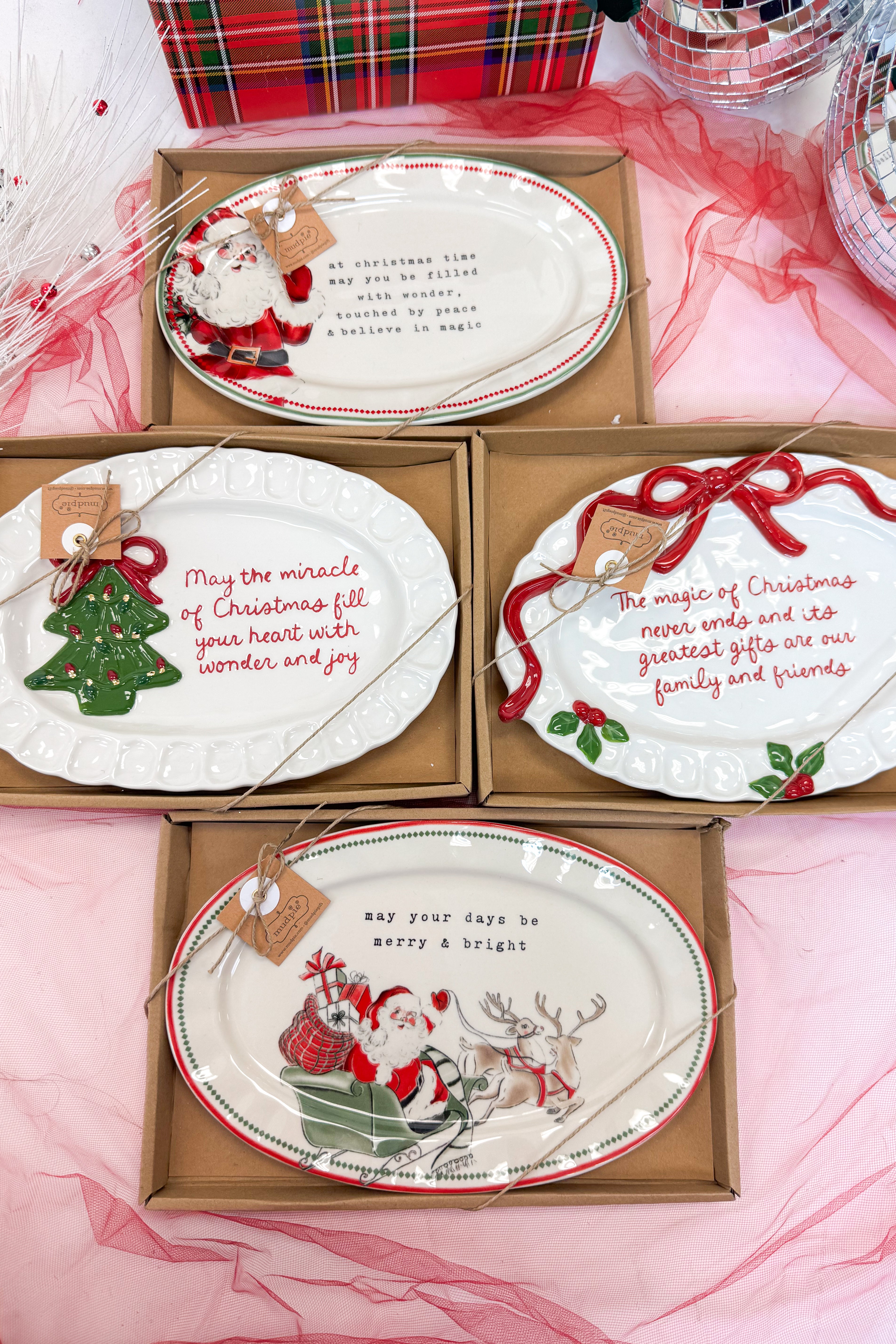 Set of Christmas-themed plates in packaging on a pink surface