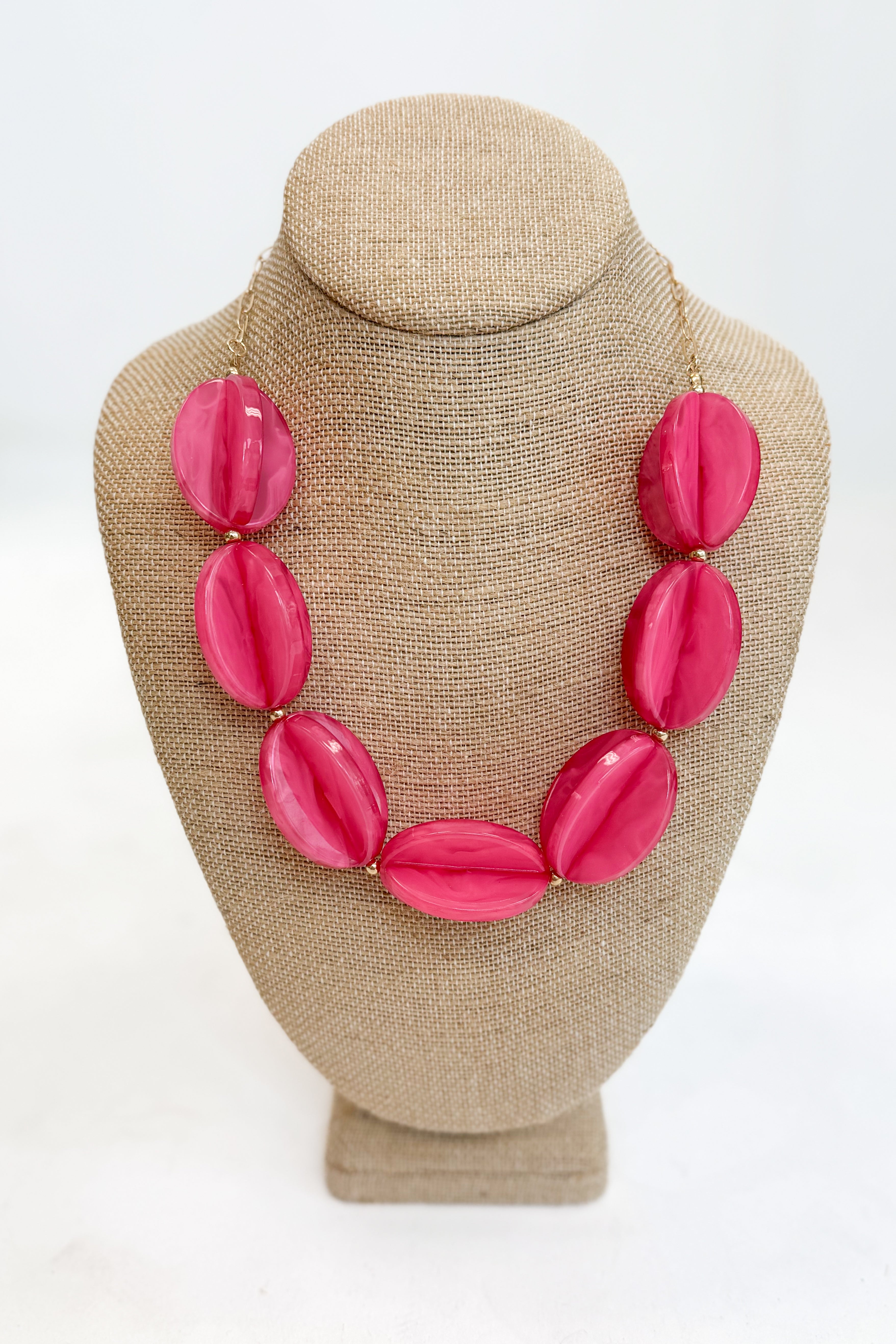 Necklace with pink beads on a beige mannequin bust against a white background