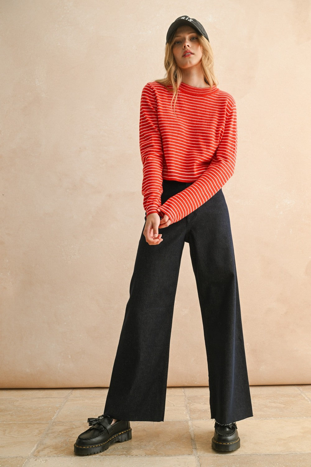 Front view of woman in a studio wearing Dark Indigo Wide Leg Jeans and print top with a tan background.