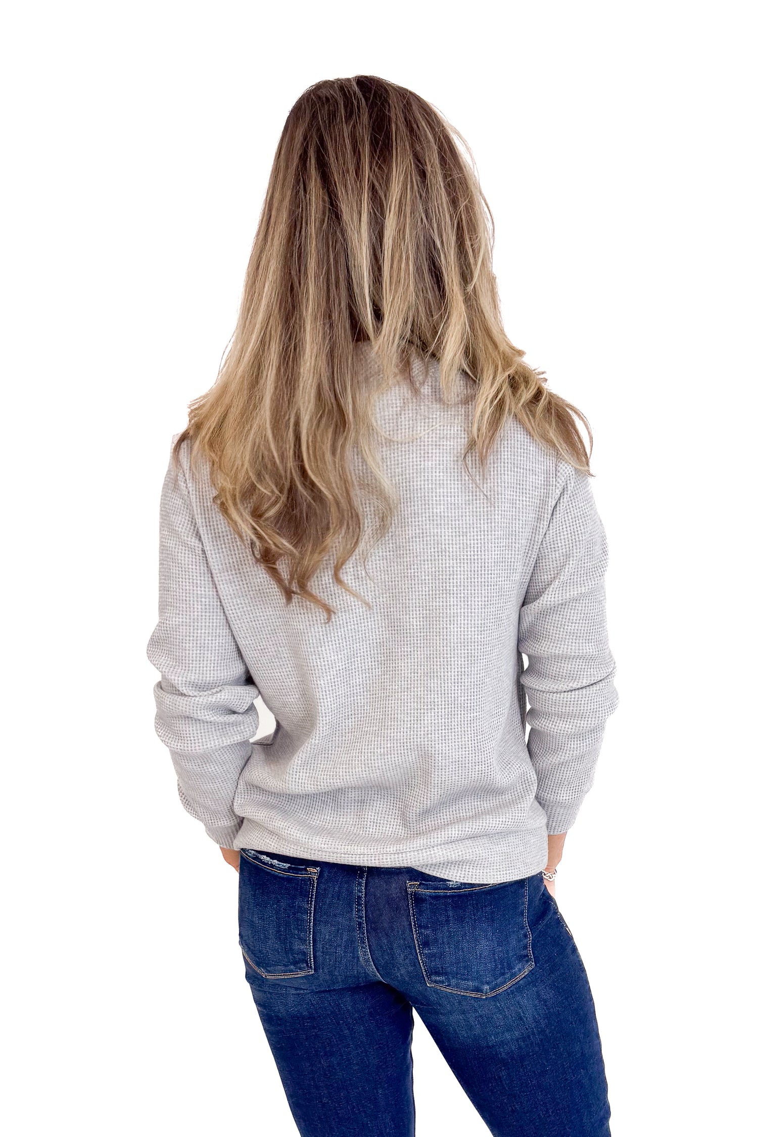 Person wearing a gray sweater and blue jeans on a white background