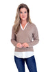 Woman wearing a brown sweater over a white shirt with blue jeans on a white background