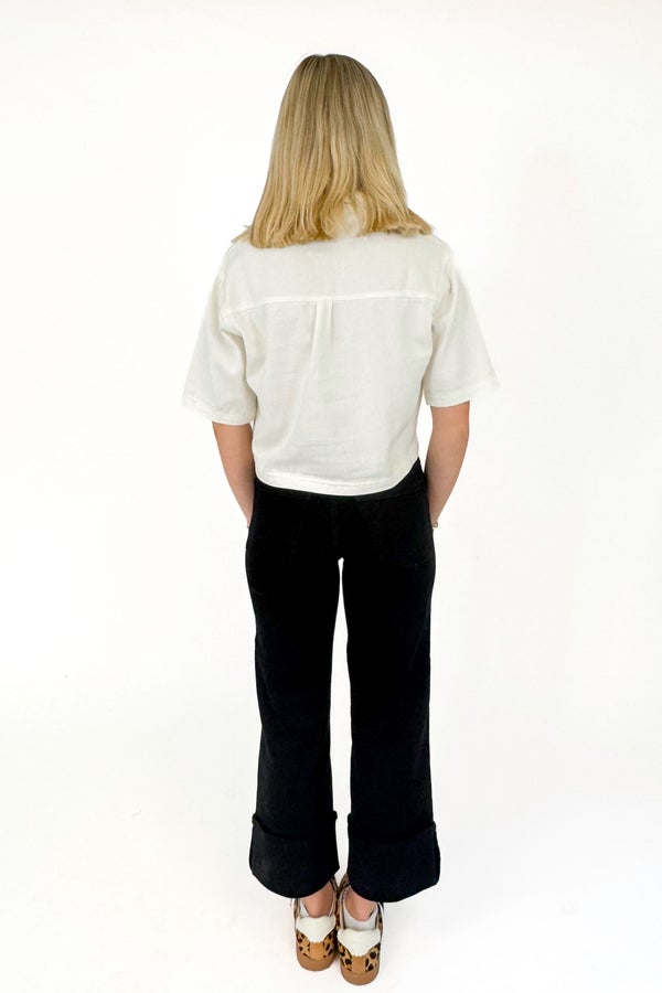 Person wearing a white shirt and black pants on a white background