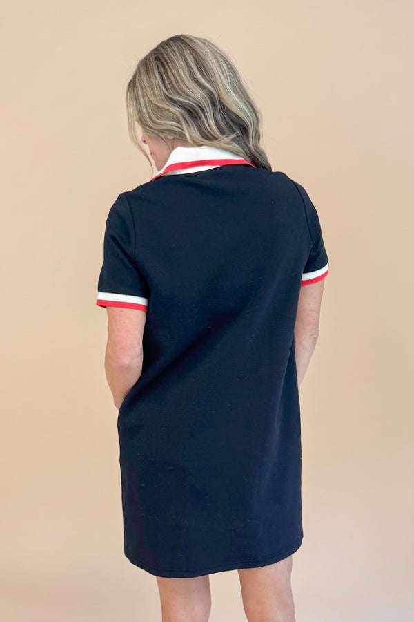 Black dress with white collar and red stripes on a beige background