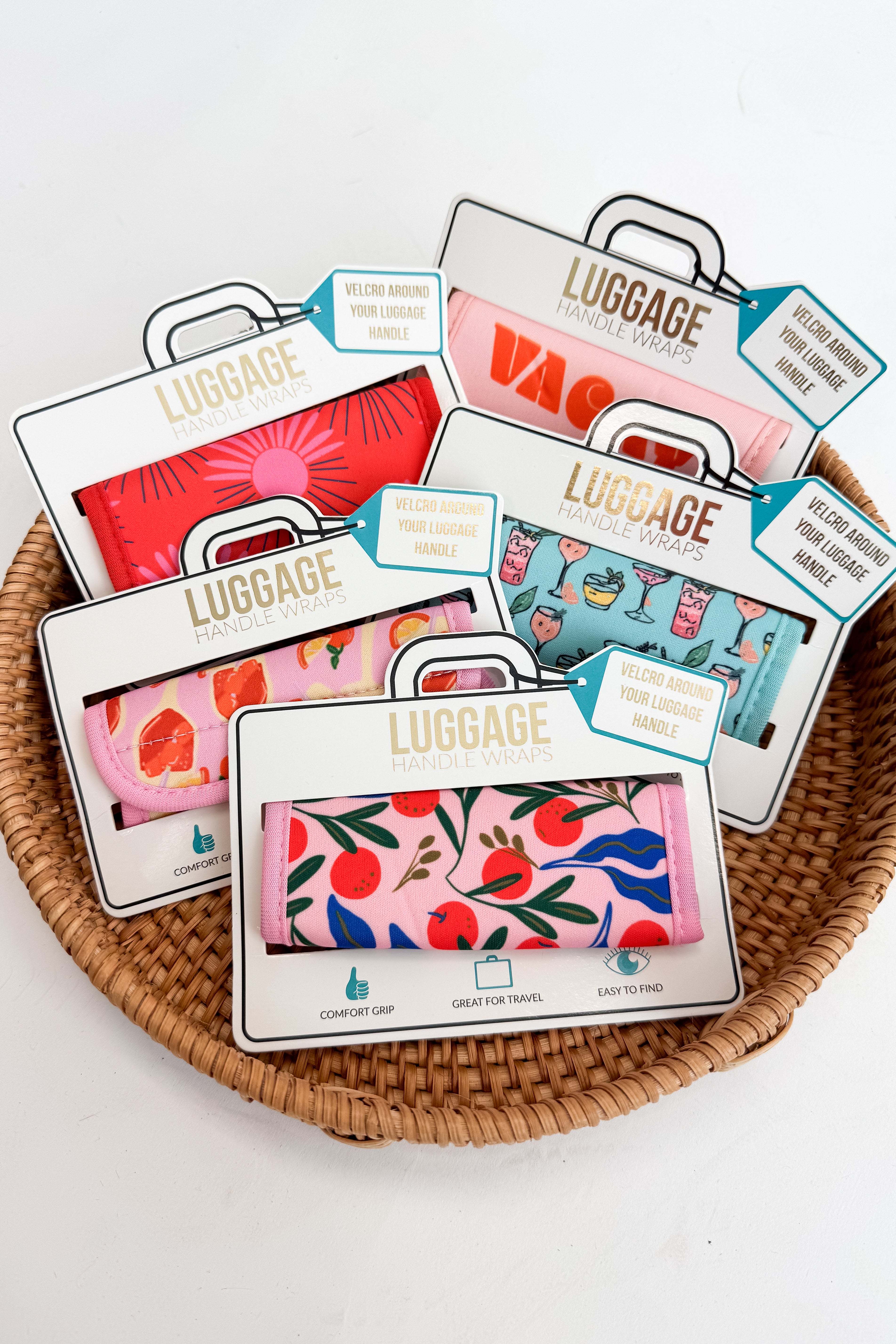 Colorful luggage tags with floral and abstract designs on a woven basket.