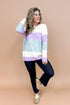 Woman wearing Lavender & Grey Colorblock Sweater and jeans with tan background.