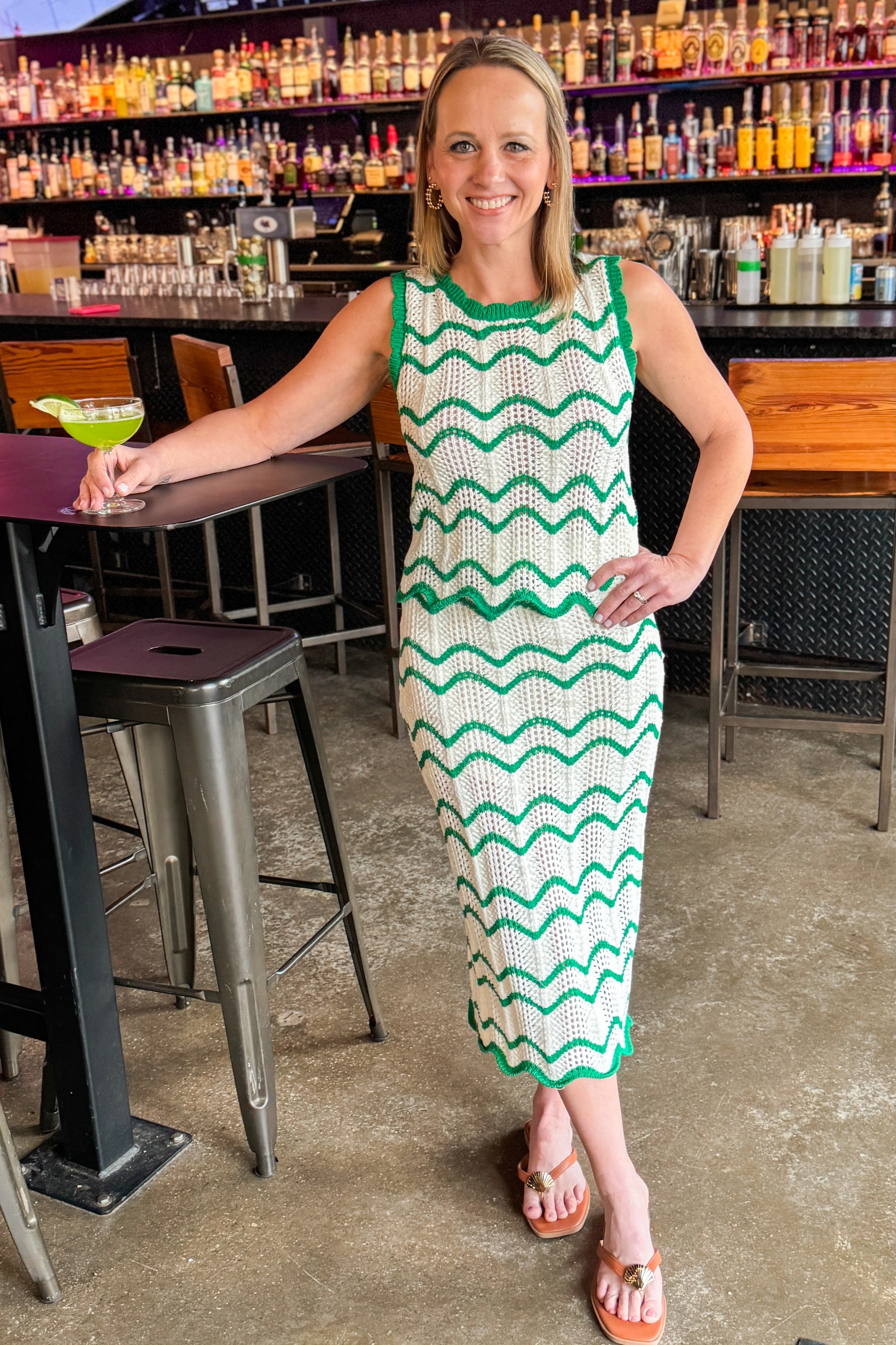 Front view of woman wearing Ivory & Green Scalloped Skirt by Skies Are Blue with matching tank at a bar.