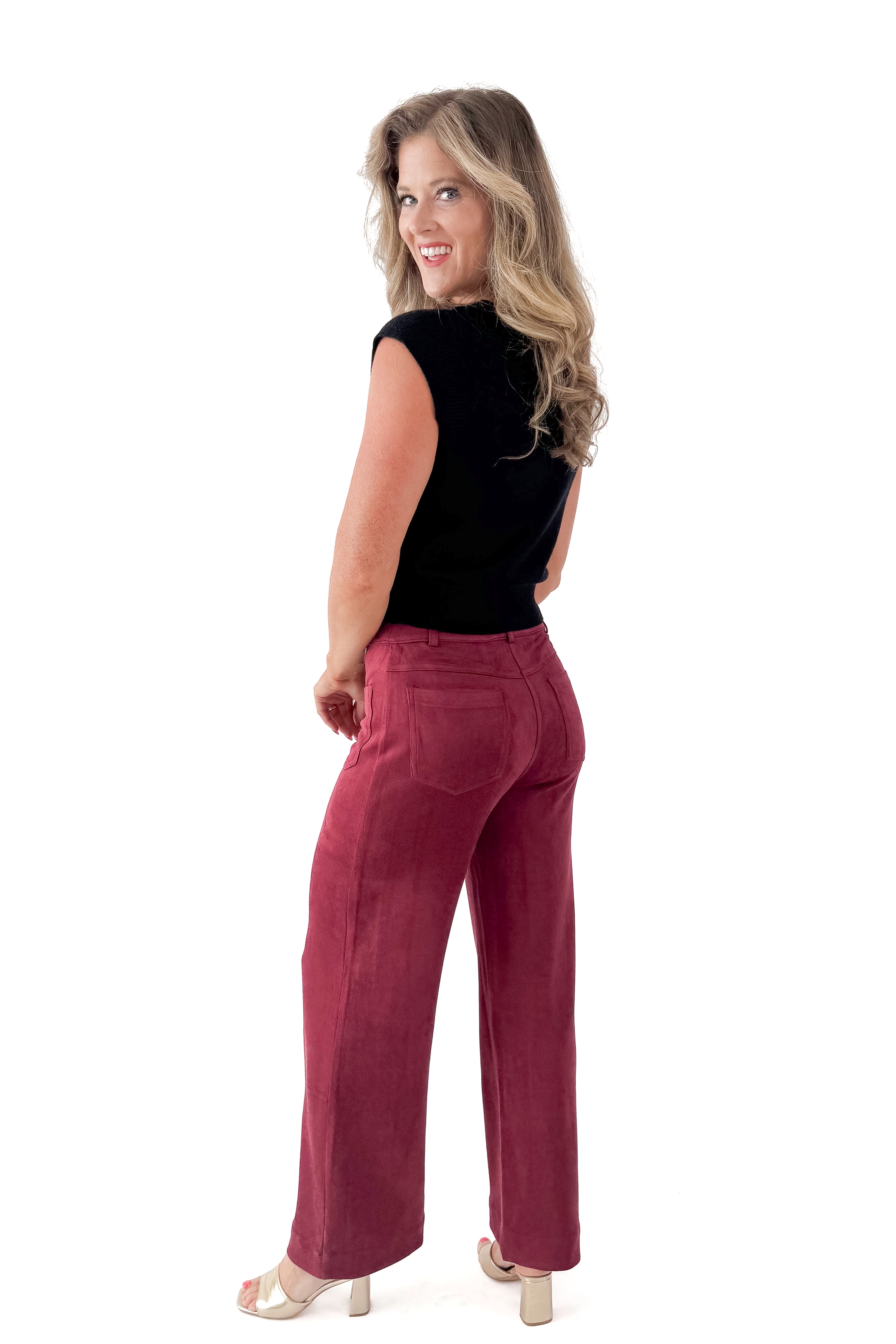 Side view of woman wearing Black Cap Sleeve Sweater with pants against white studio background.