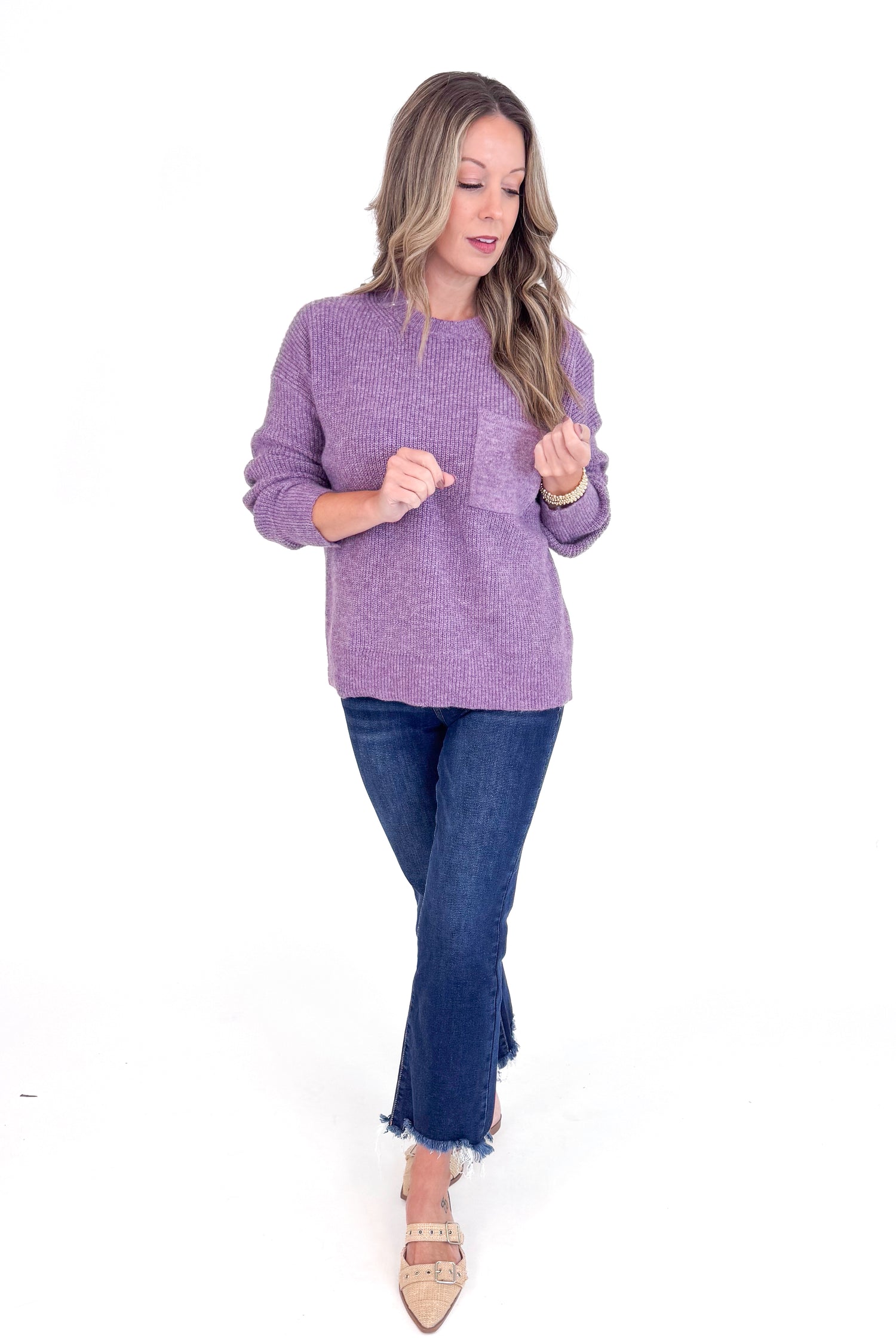 Woman wearing a purple sweater and jeans on a white background