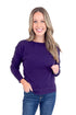 Woman wearing a purple sweater and blue jeans on a white background