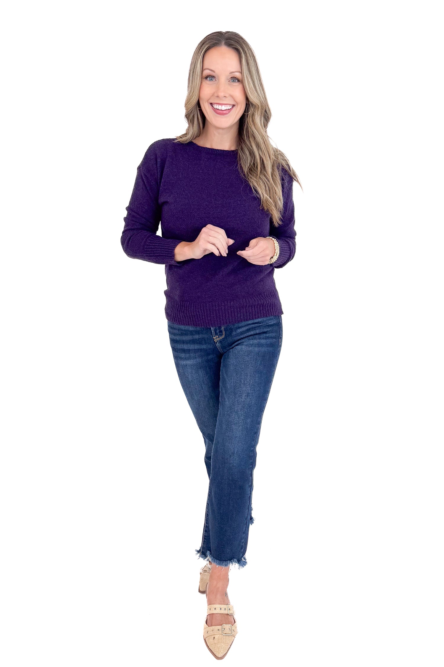 Woman wearing a purple sweater and blue jeans on a white background