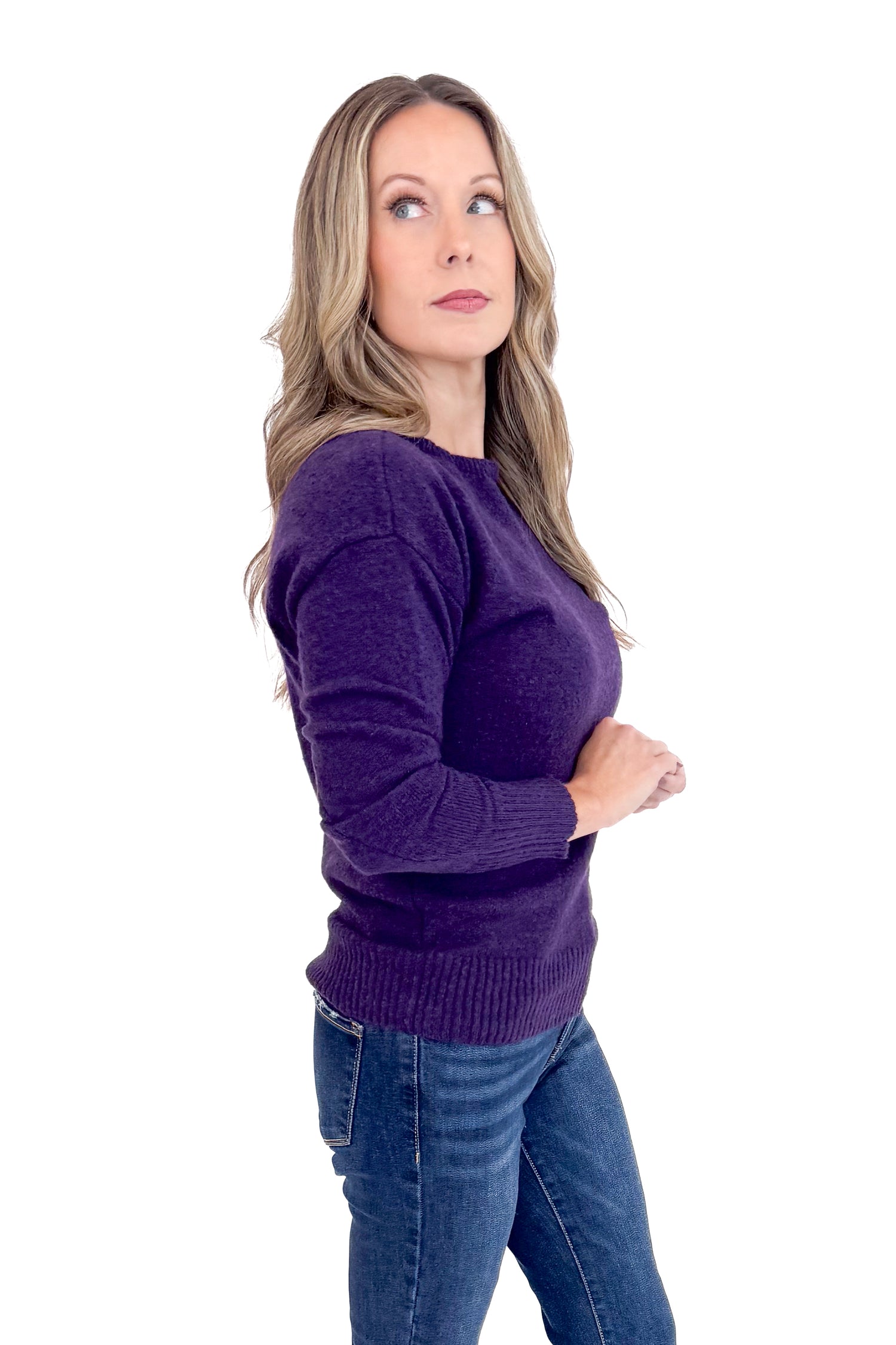 Woman wearing a purple sweater and blue jeans on a white background