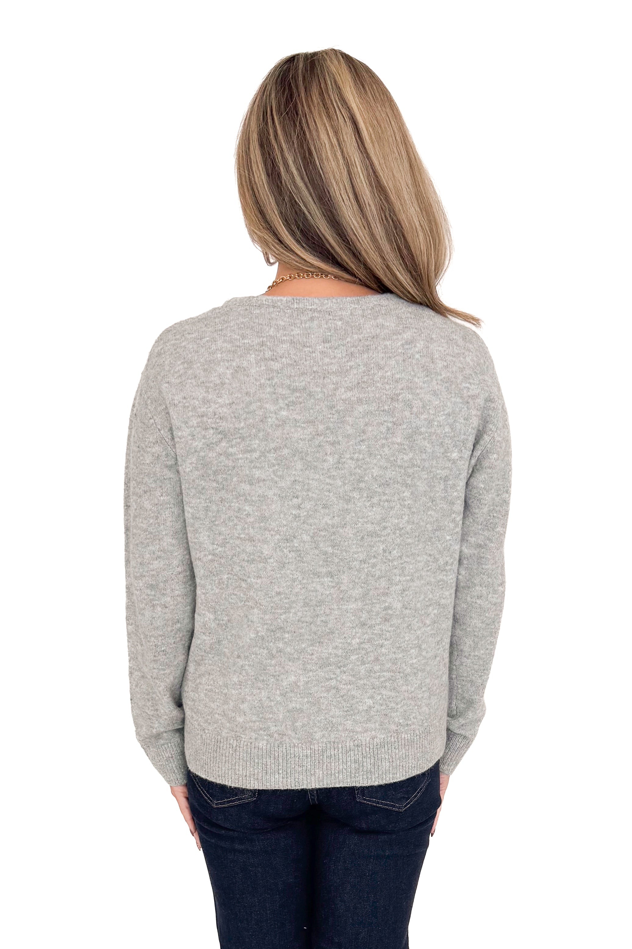 Back view of woman wearing Grey Bow Printed Sweater with jeans against white studio background.