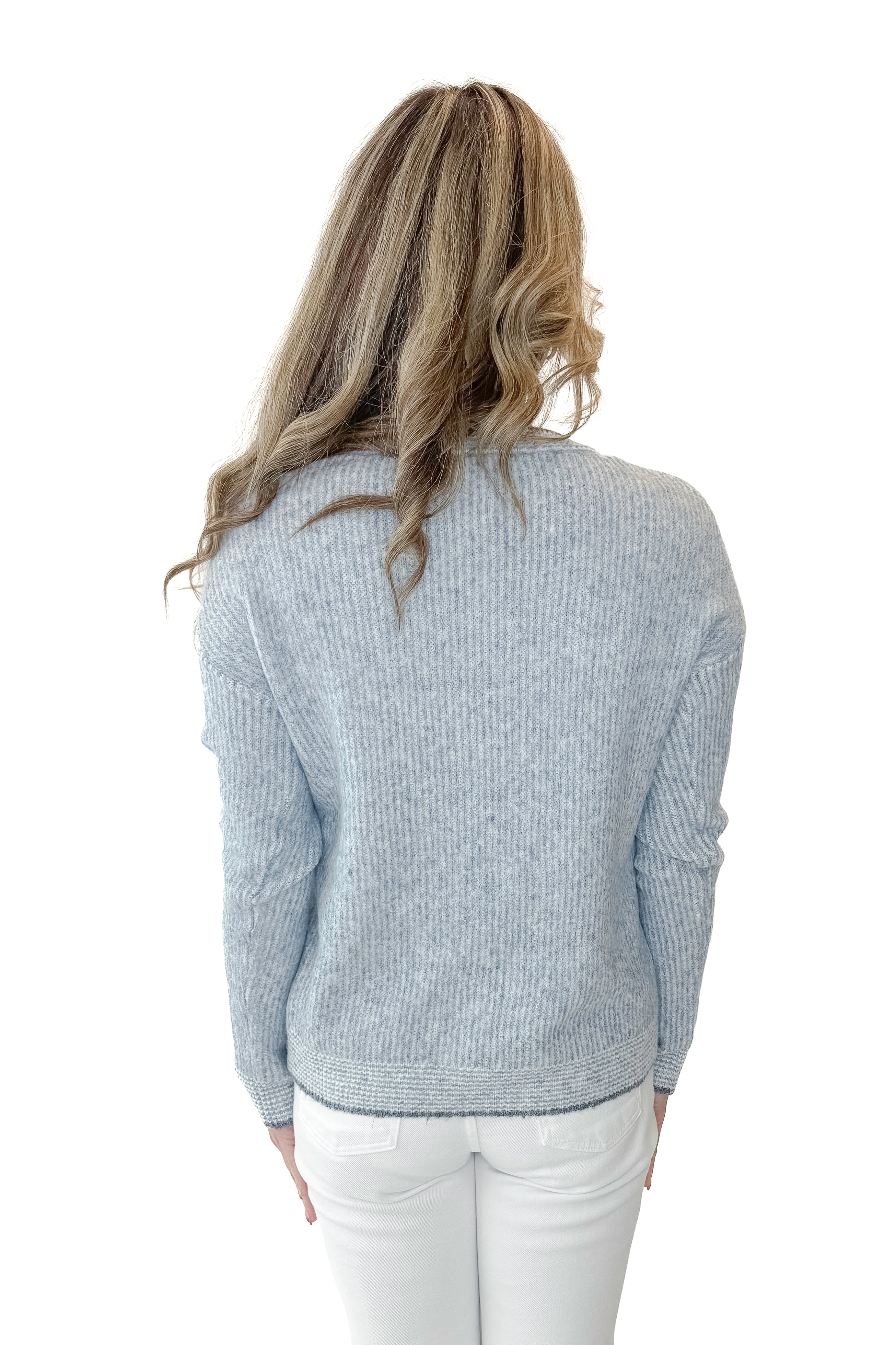 Back view of woman wearing Light Blue Ribbed Sweater with white jeans against a white background.