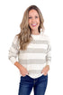 Woman wearing a white and gray striped sweater with blue jeans on a white background