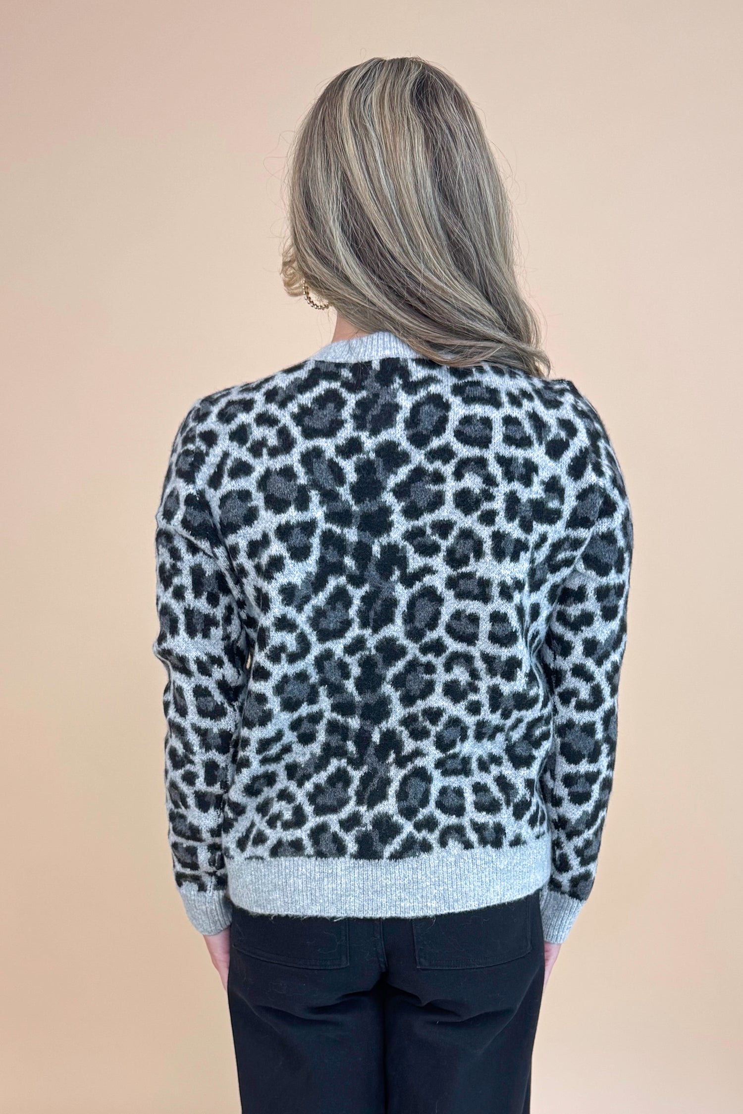 Back view of woman wearing Grey Leopard Button Up Cardigan and black jeans.