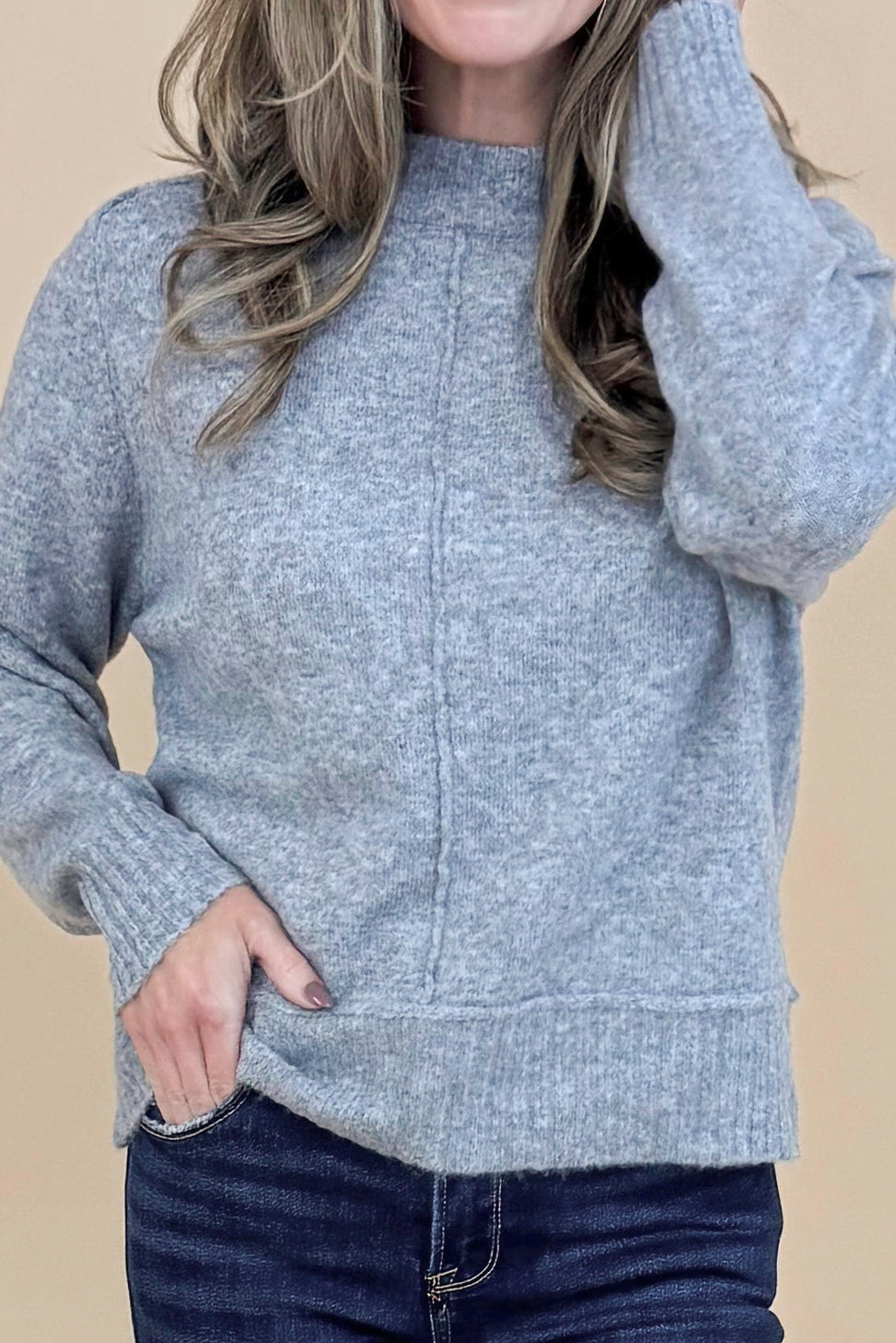 Detailed front view of woman wearing Grey Center Seam Detail Sweater and blue jeans.