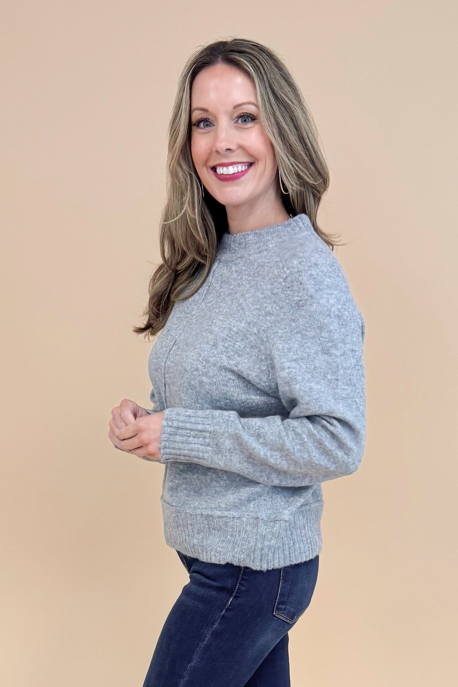 Side view of woman wearing Grey Center Seam Detail Sweater and blue jeans.