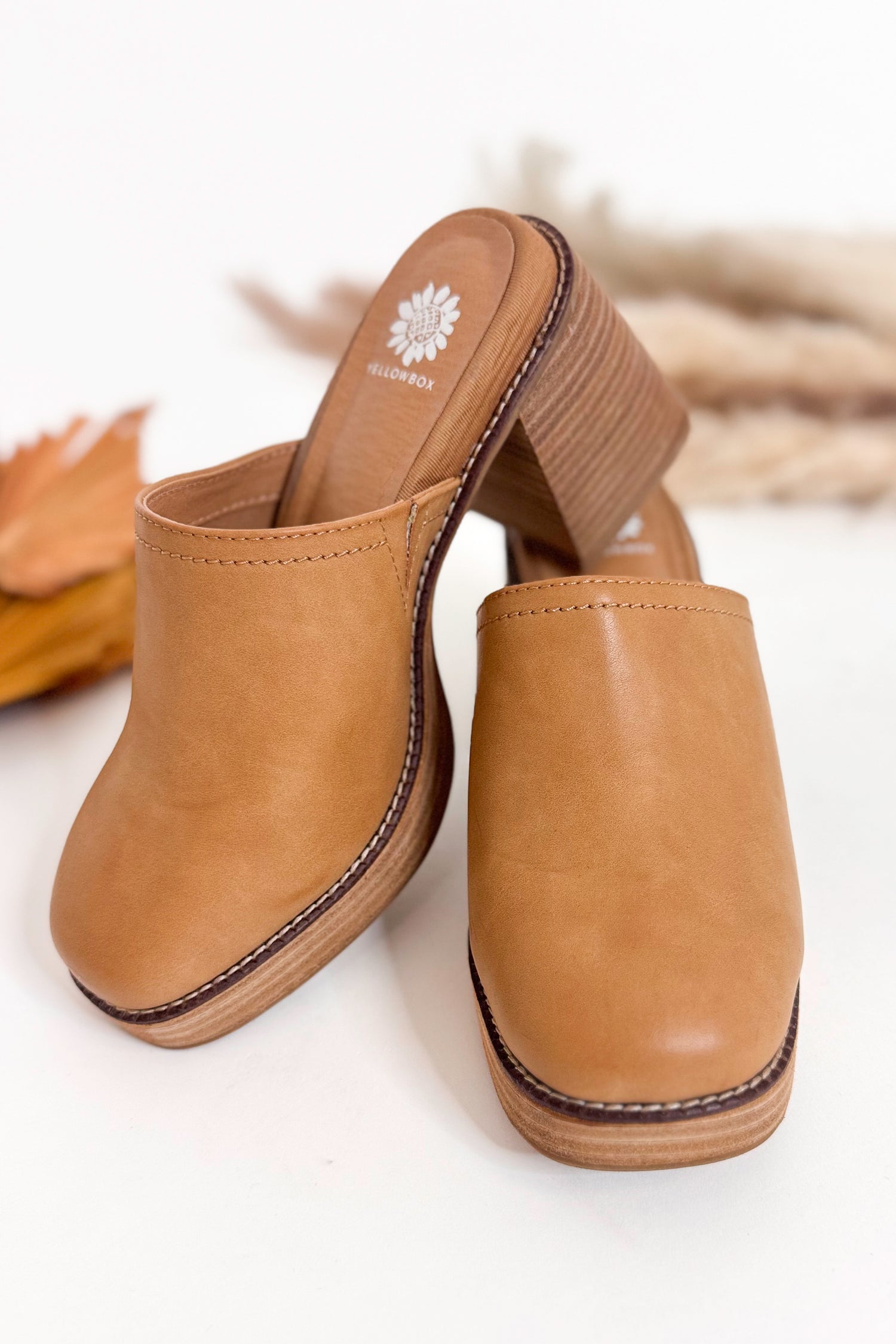 Tan clogs with a visible brand logo on a white background