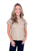 Front view of woman wearing taupe faux leather top with jeans against white studio background.