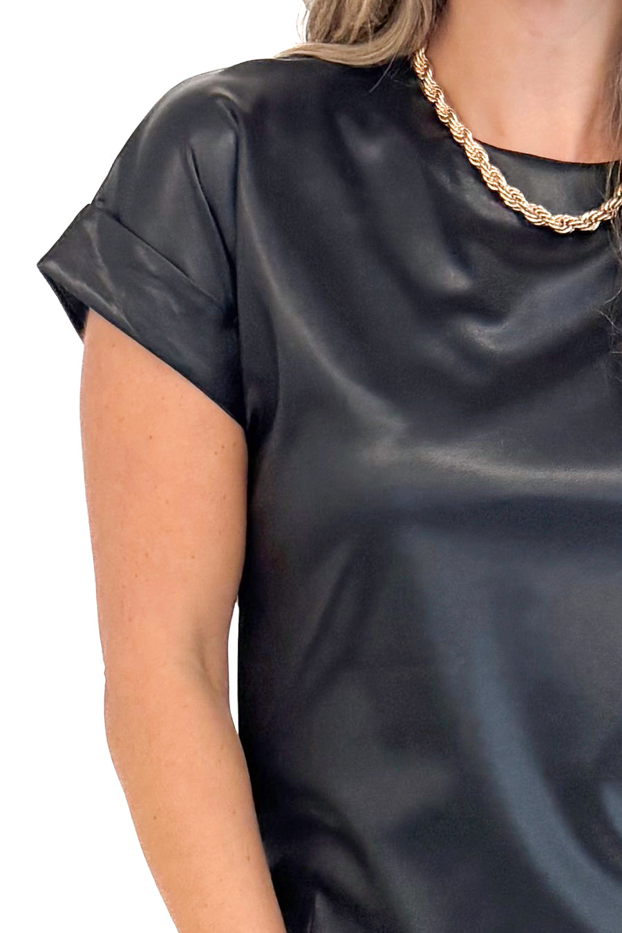 Up close detailed picture of woman wearing black faux leather cap sleeve top with round neckline.