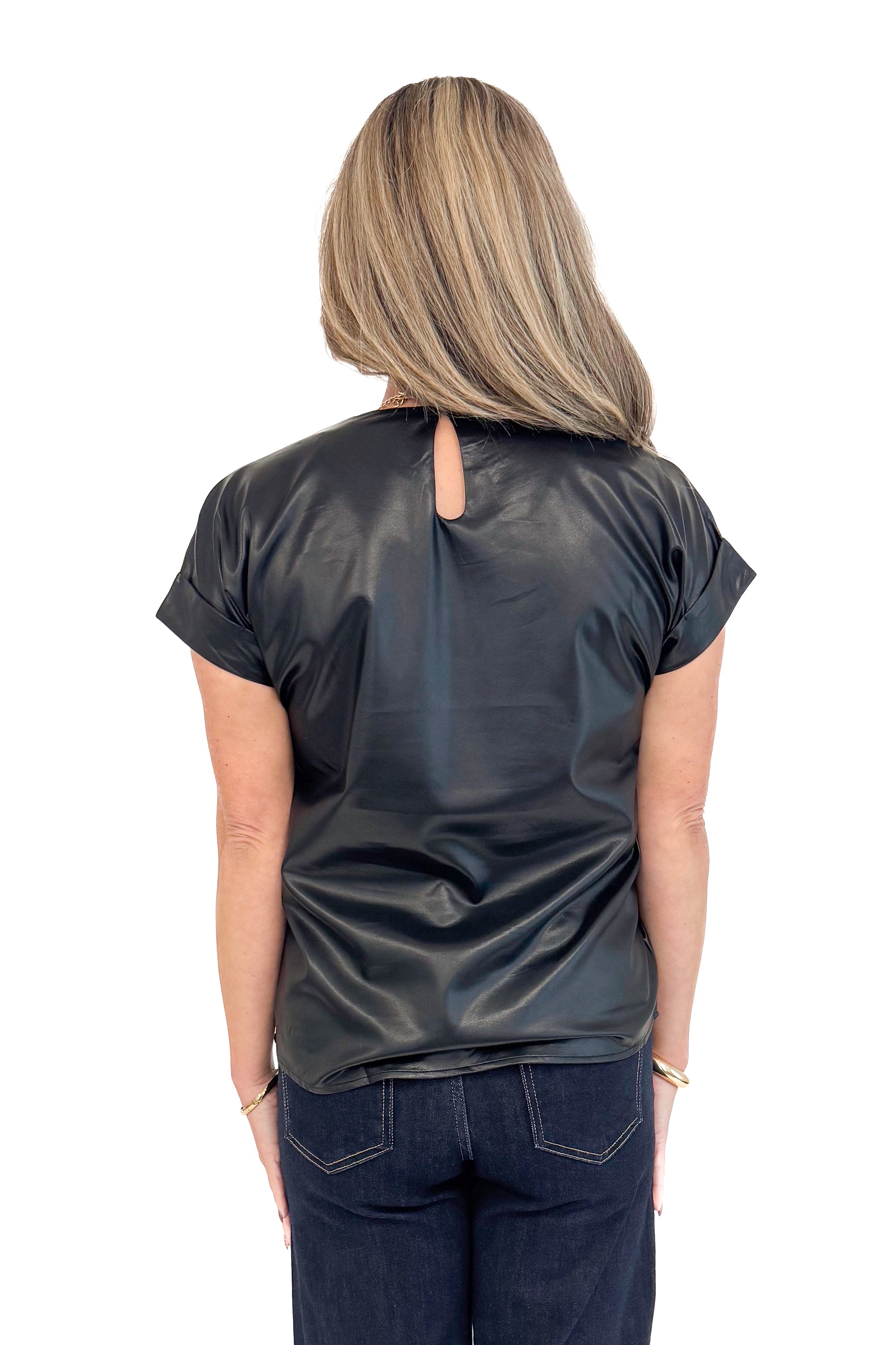 Back view of woman wearing black faux leather cap sleeve top with round neckline and blue jeans.